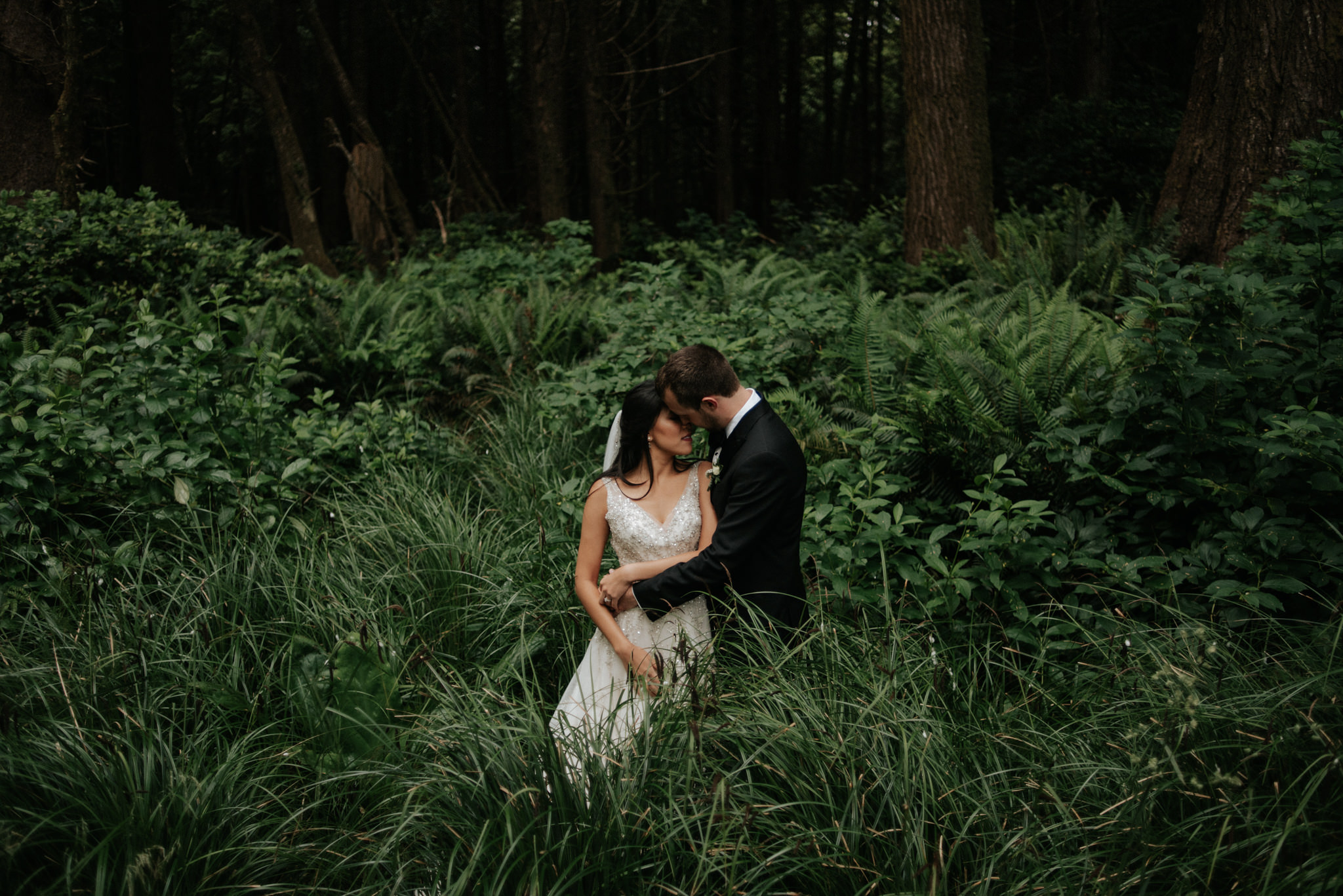 Couple standing in sea grass in forest in Tofino