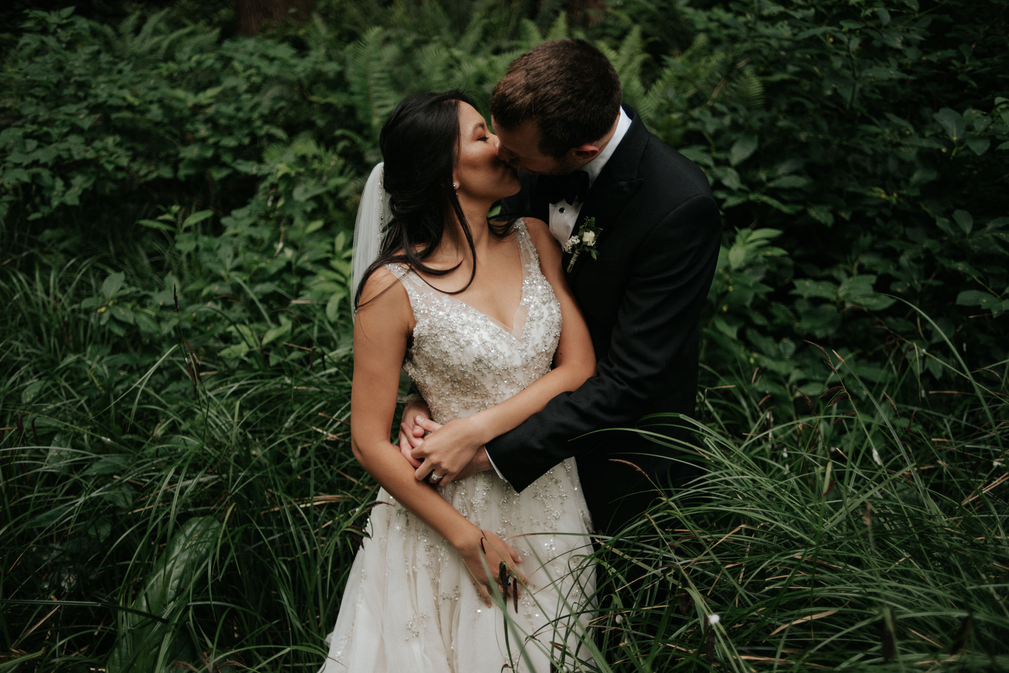 Couple standing in sea grass in forest in Tofino