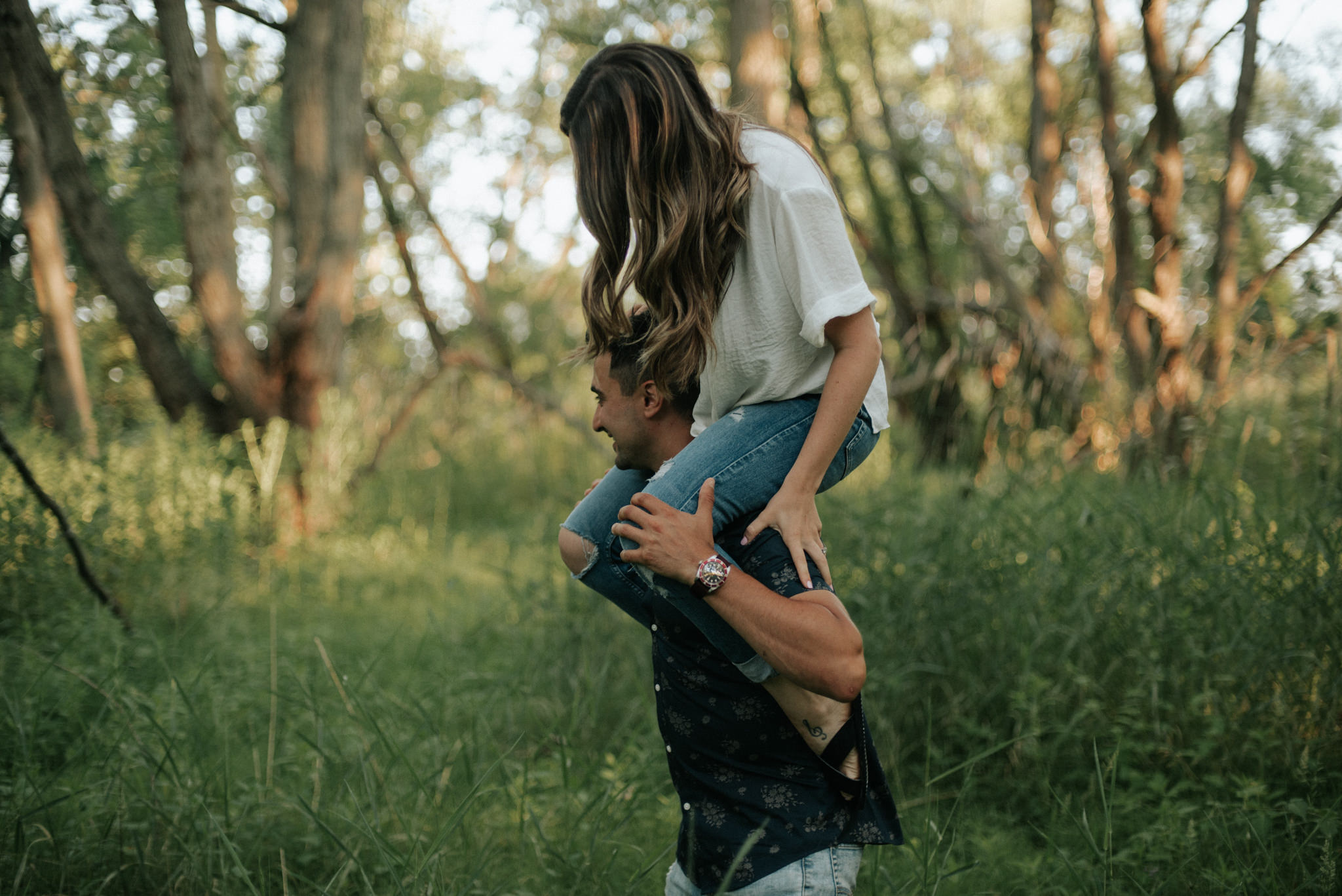 girl sitting on guy's shoulders in a forest