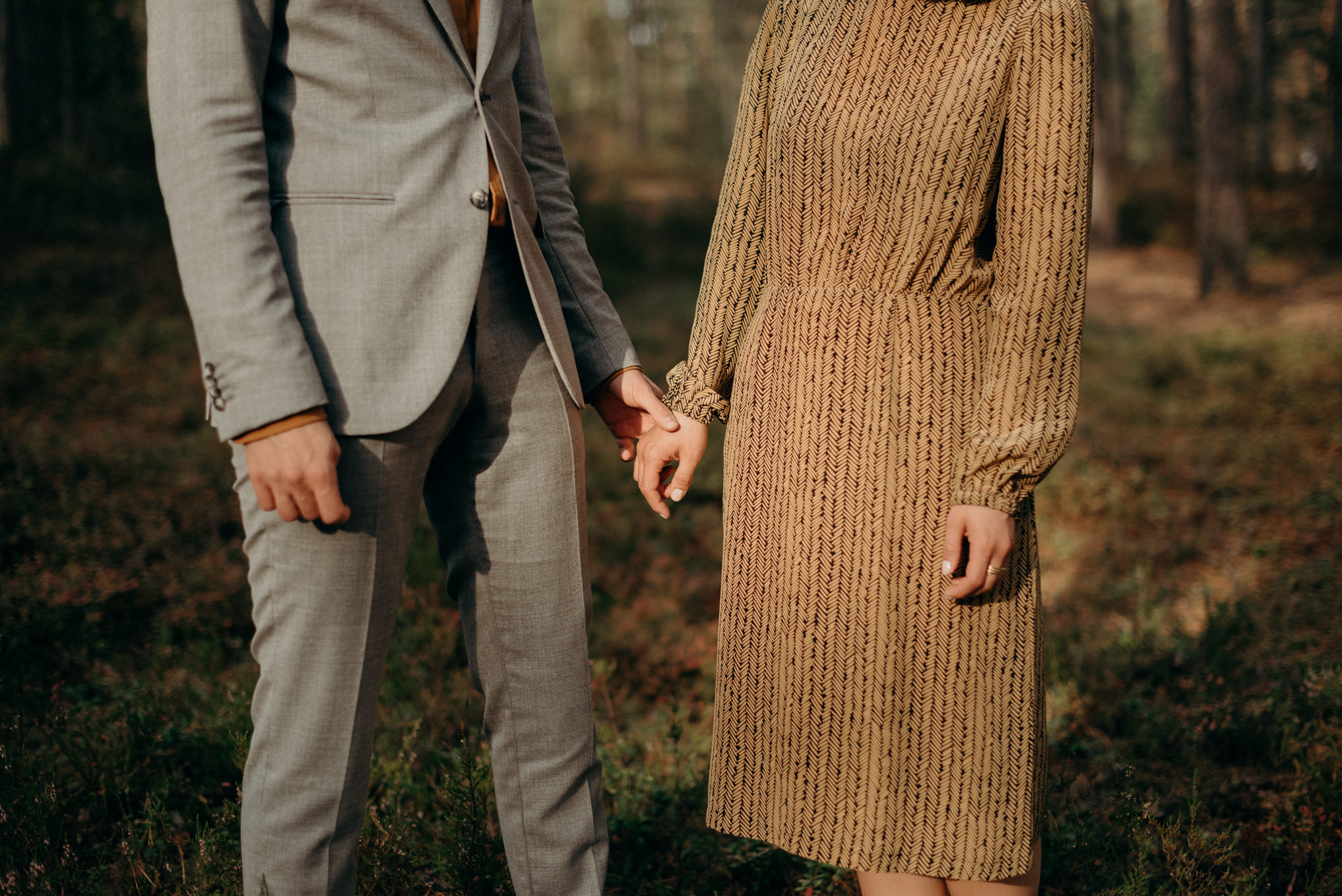 couple holding hands in sunlight in forest