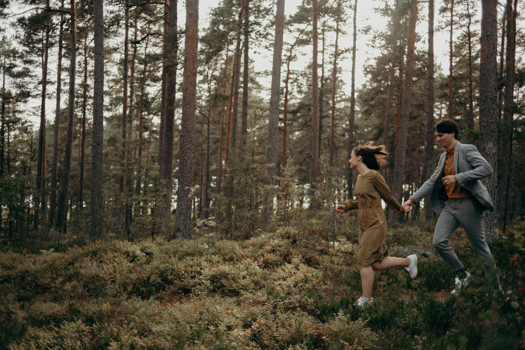 couple holding hands and running in forest