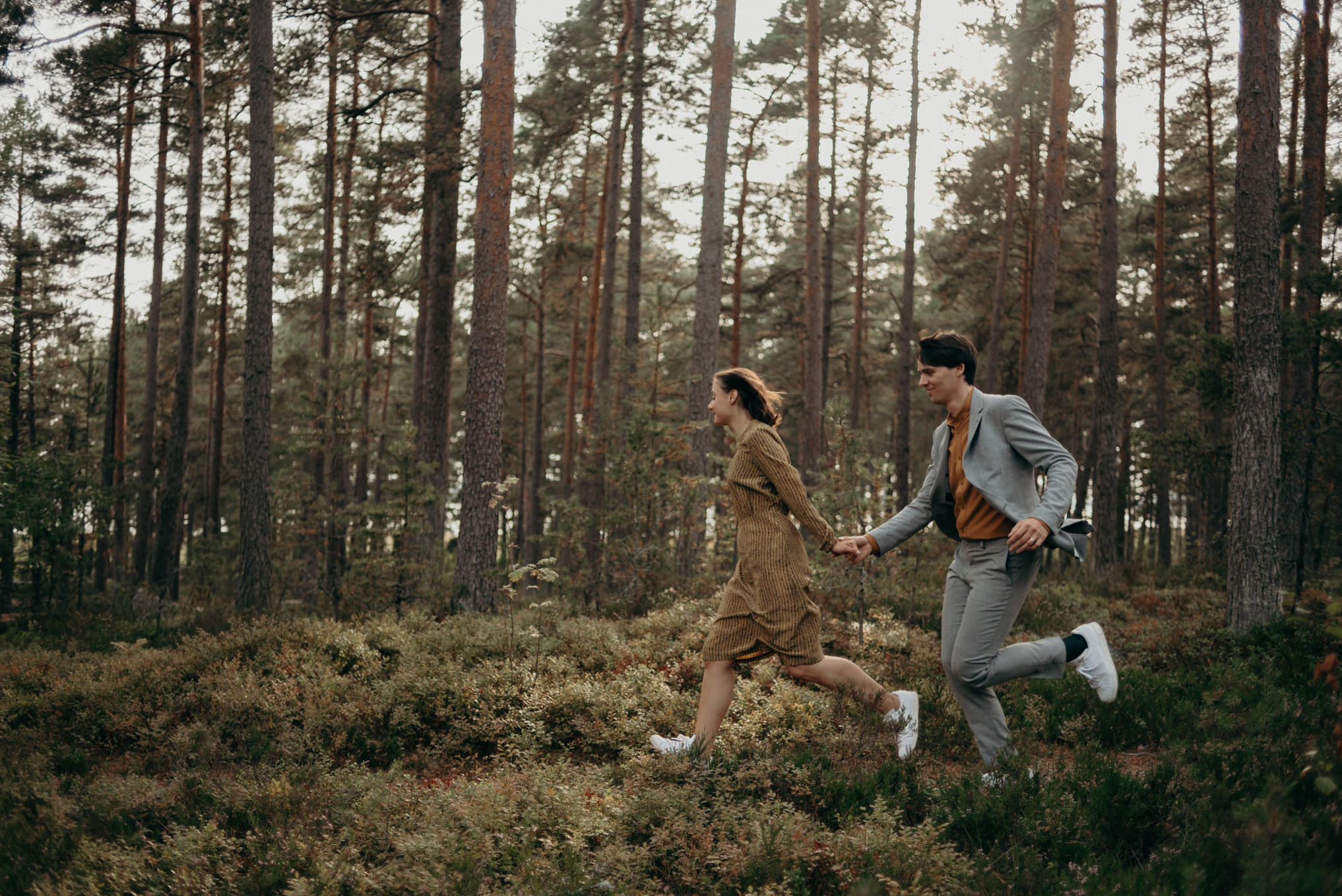 couple holding hands and running in forest