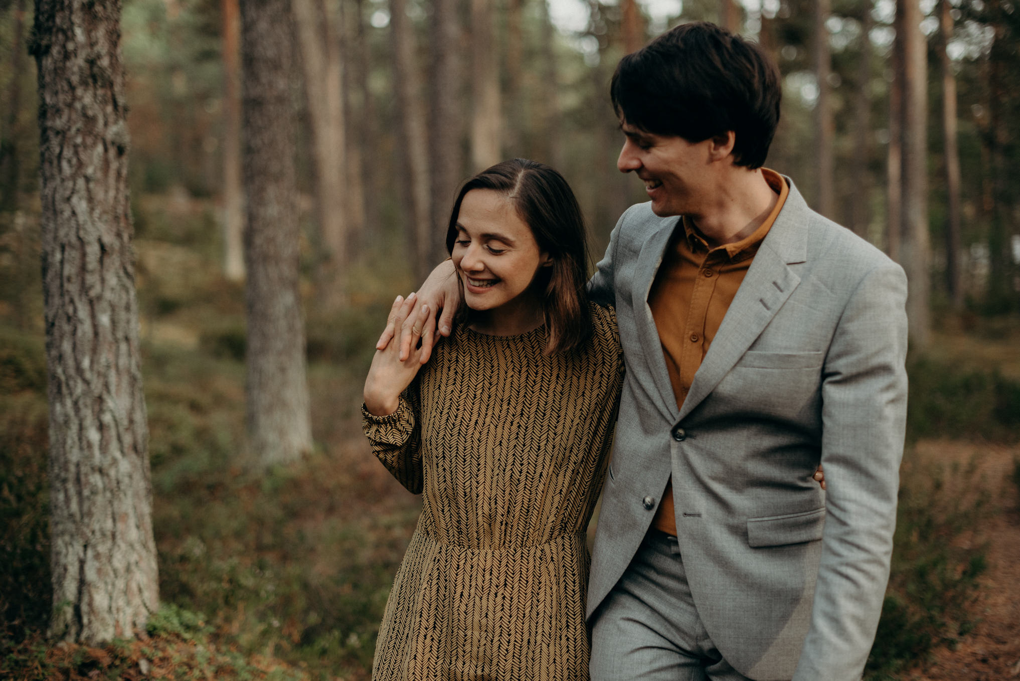 couple laughing and walking in forest