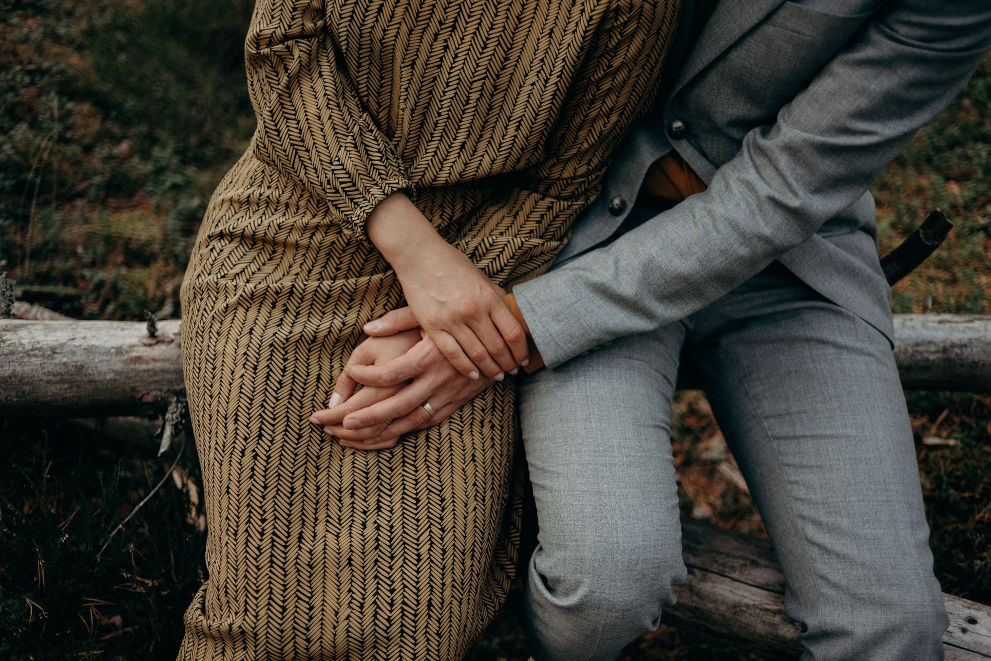 couple sitting on log holding hands