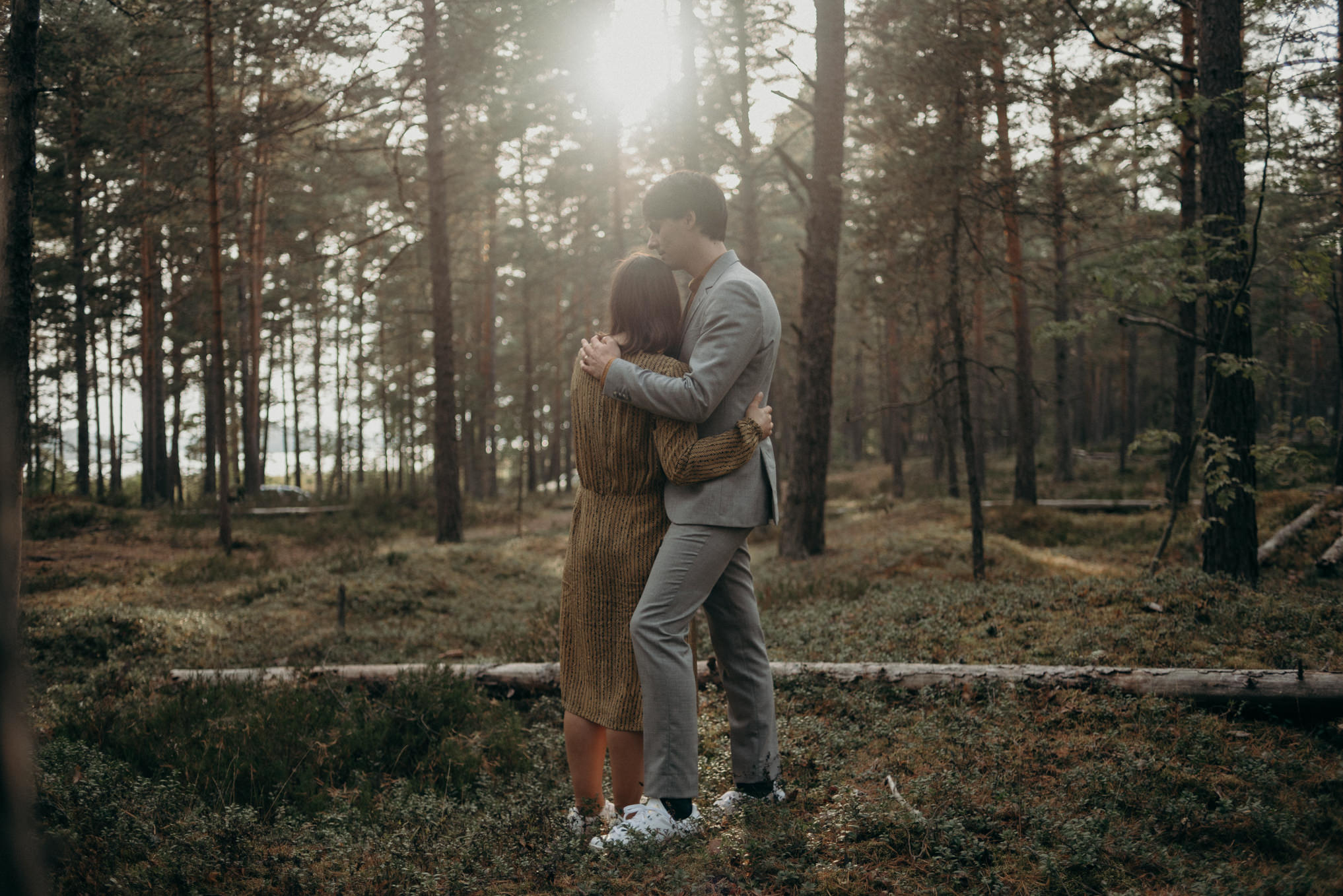 couple standing in patch of sun in forest