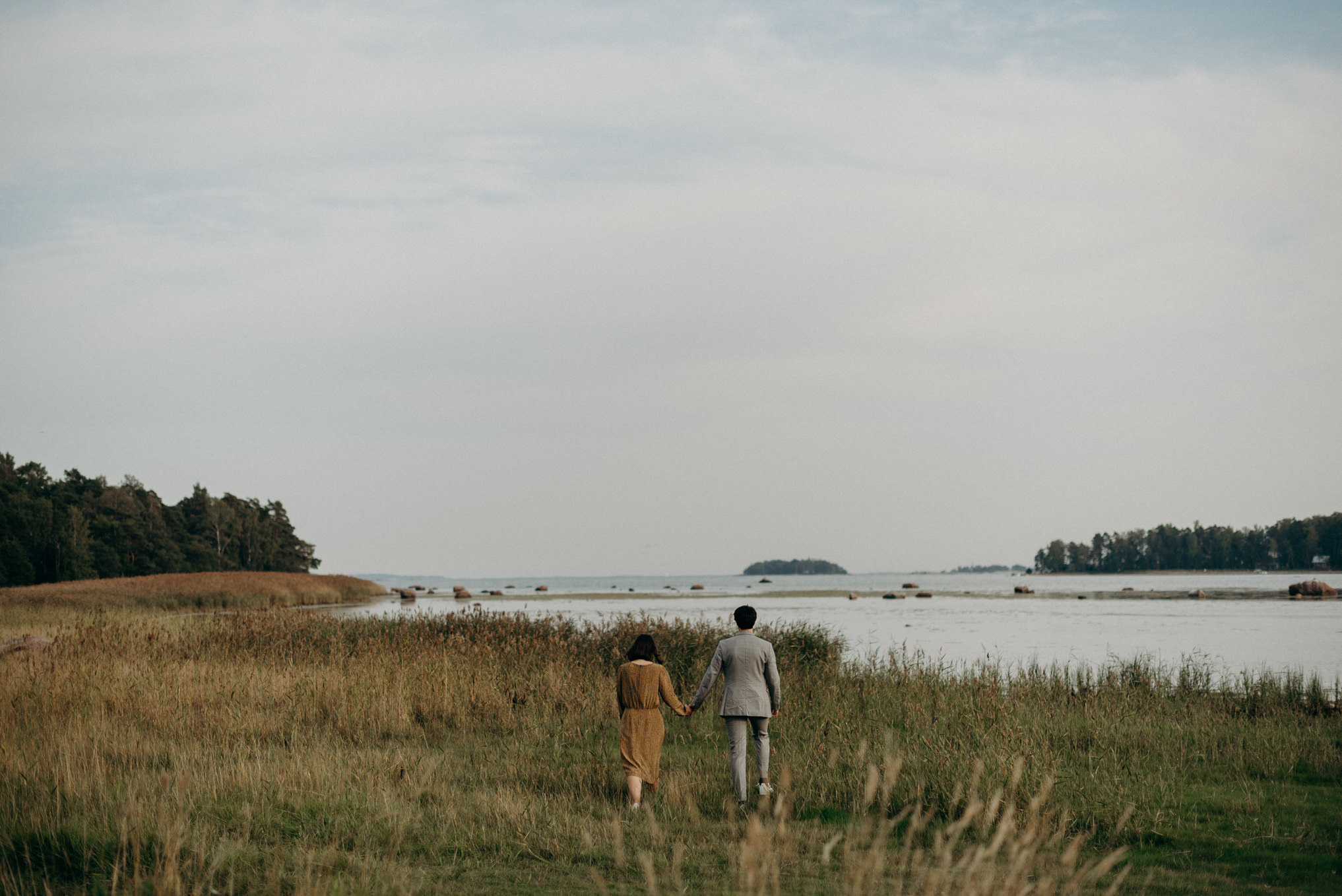 couple walking in grass towards water