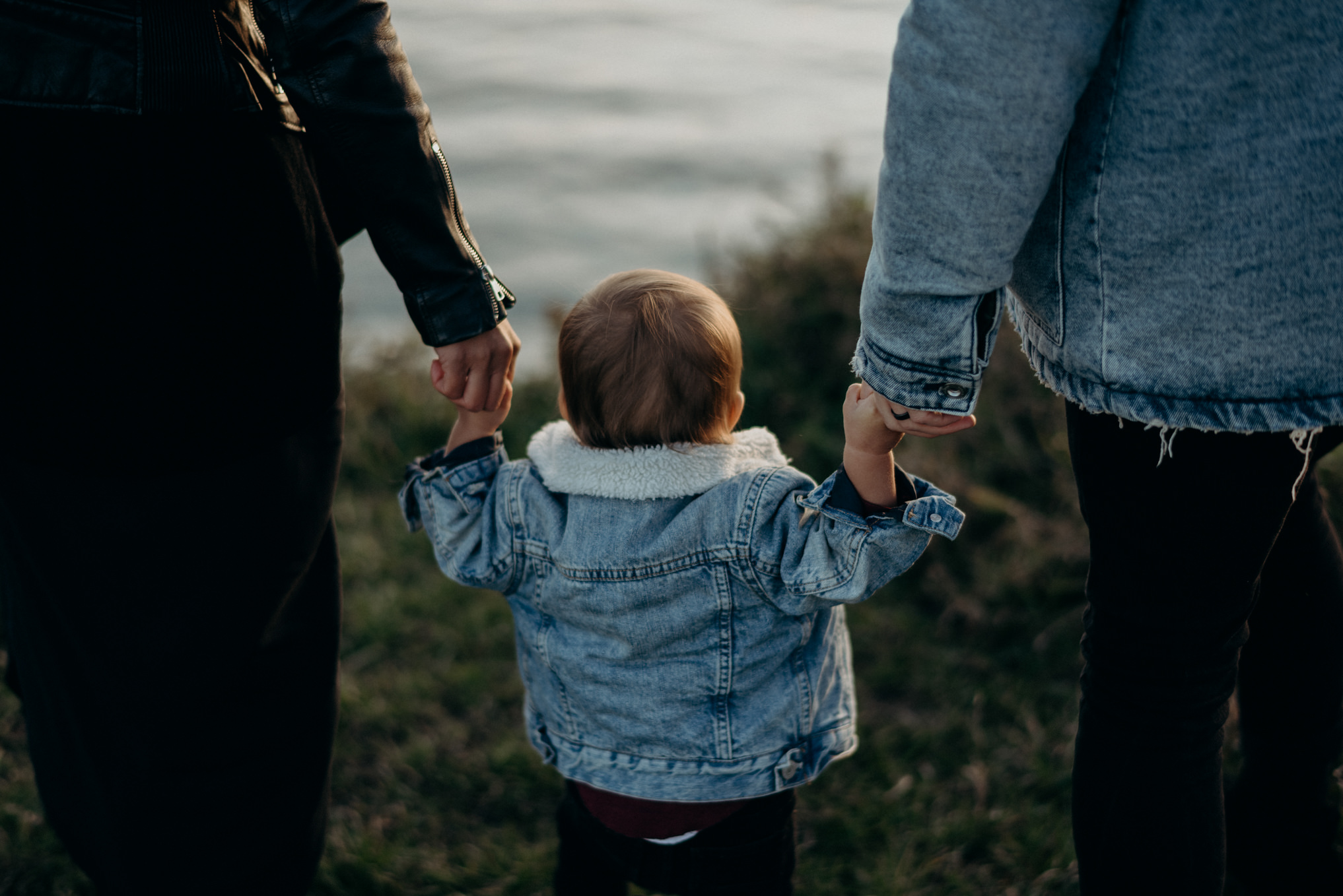 mom and dad holding baby boys hands while walking