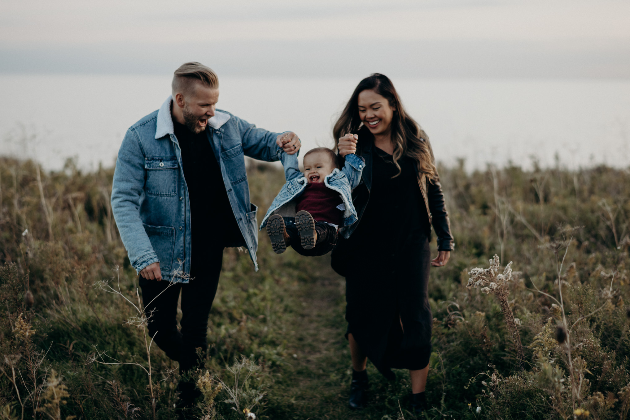 Young couple swinging baby boy in the air by hands