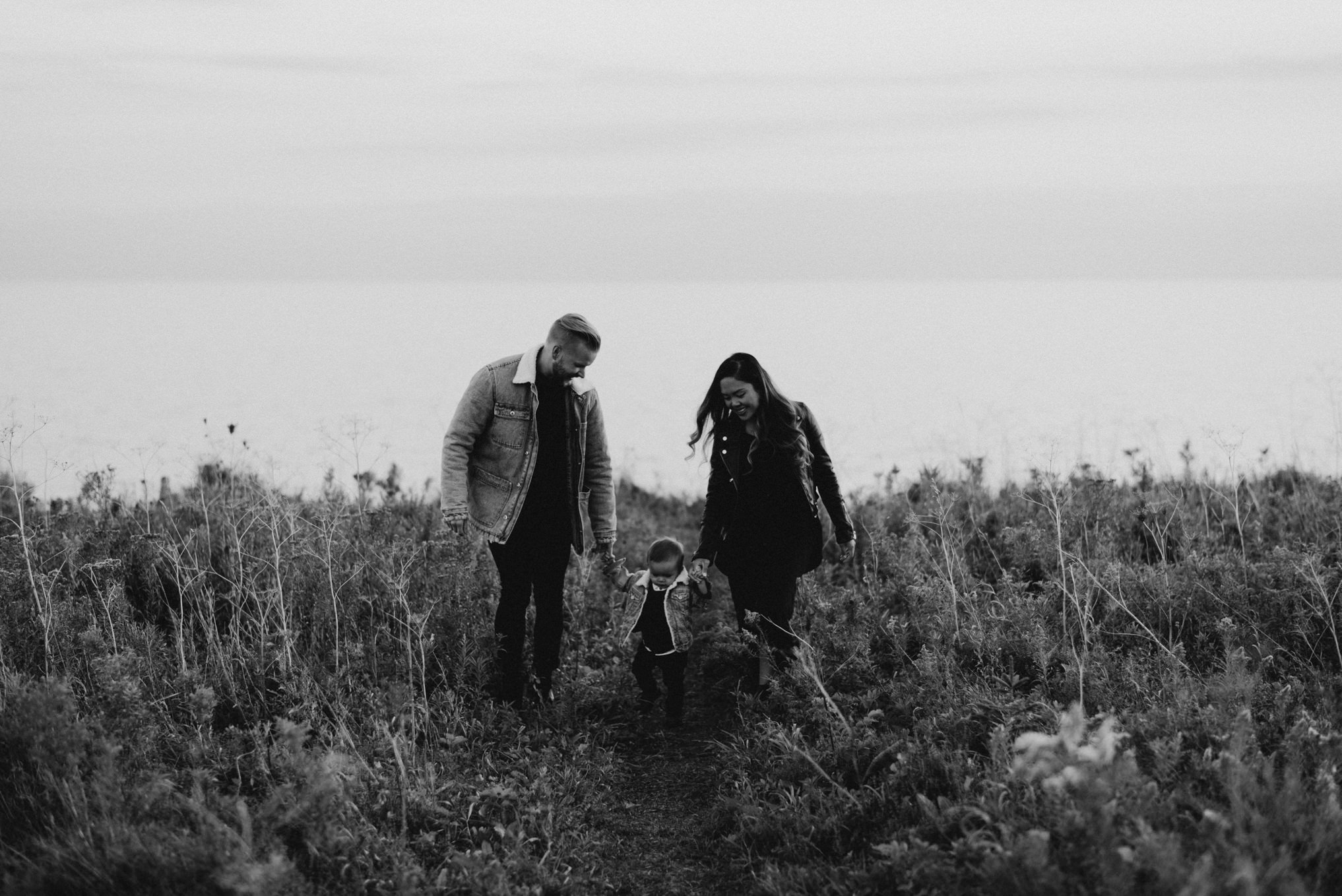 young couple and mixed baby boy walking in tall grass