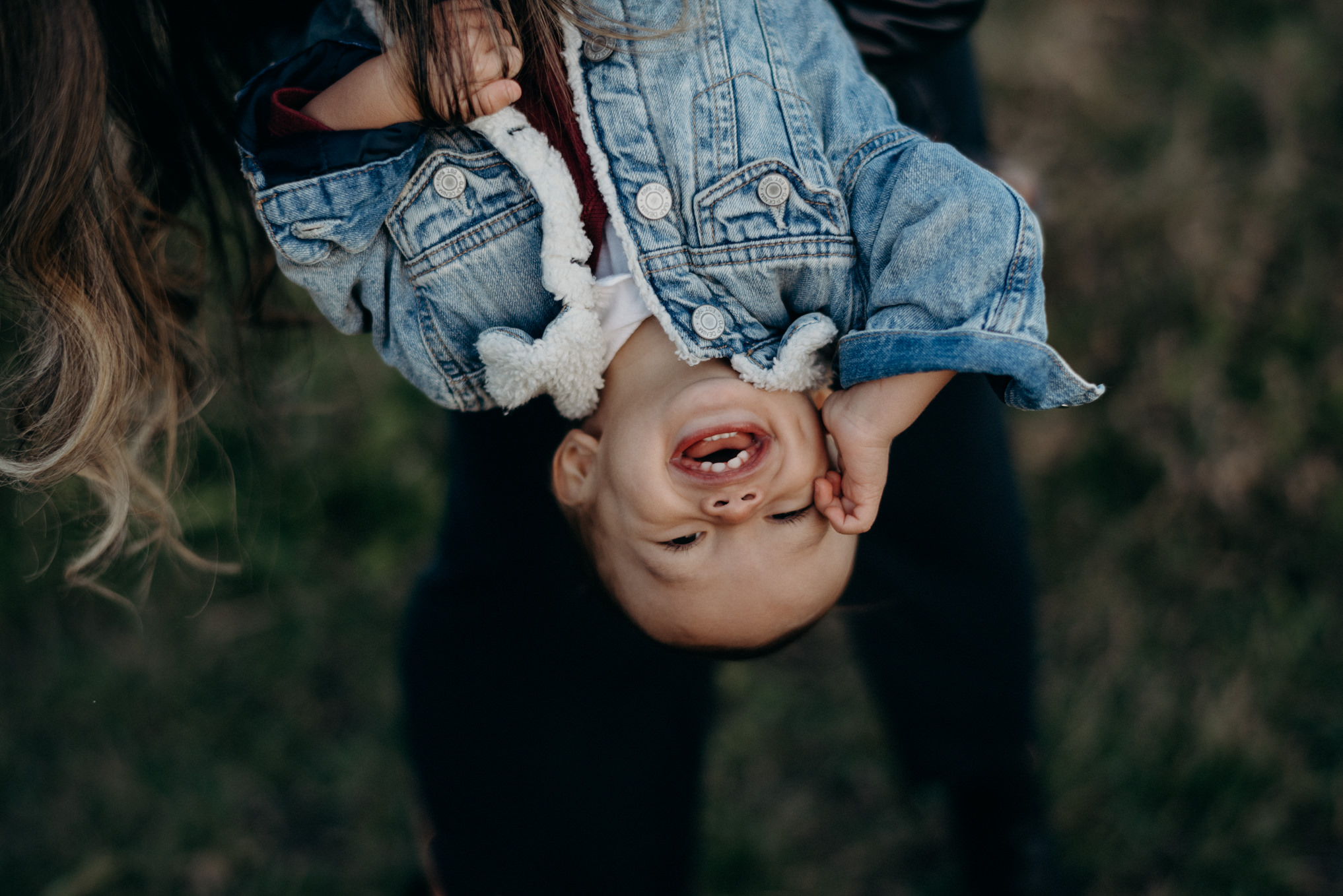 mom holding baby boy upside down and showing his teeth