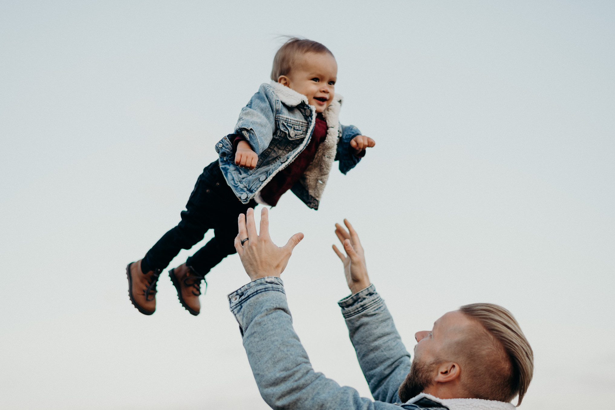 dad throwing baby boy in air with matching jean jacket