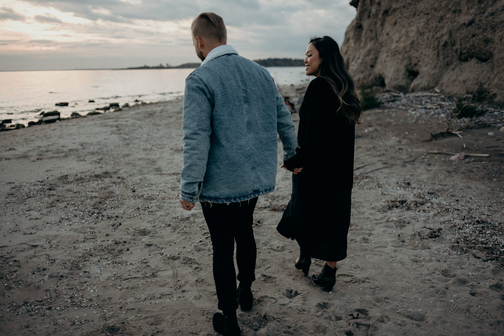 filipino woman and white guy mixed race couple smiling and looking at sunset by water