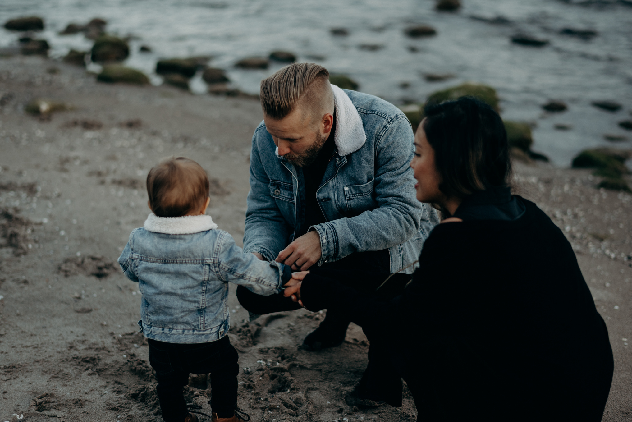 young hip couple holding baby boy on the beach