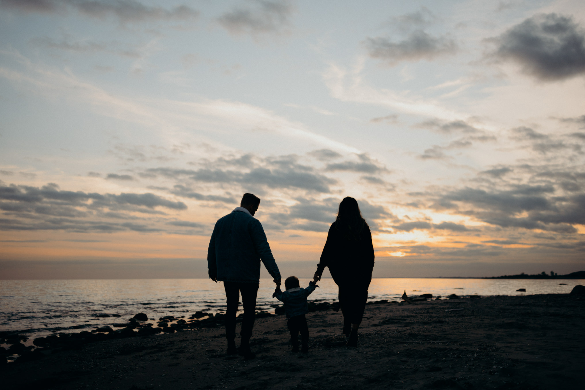 Portrait of young family watching sunset on the beach in Toronto