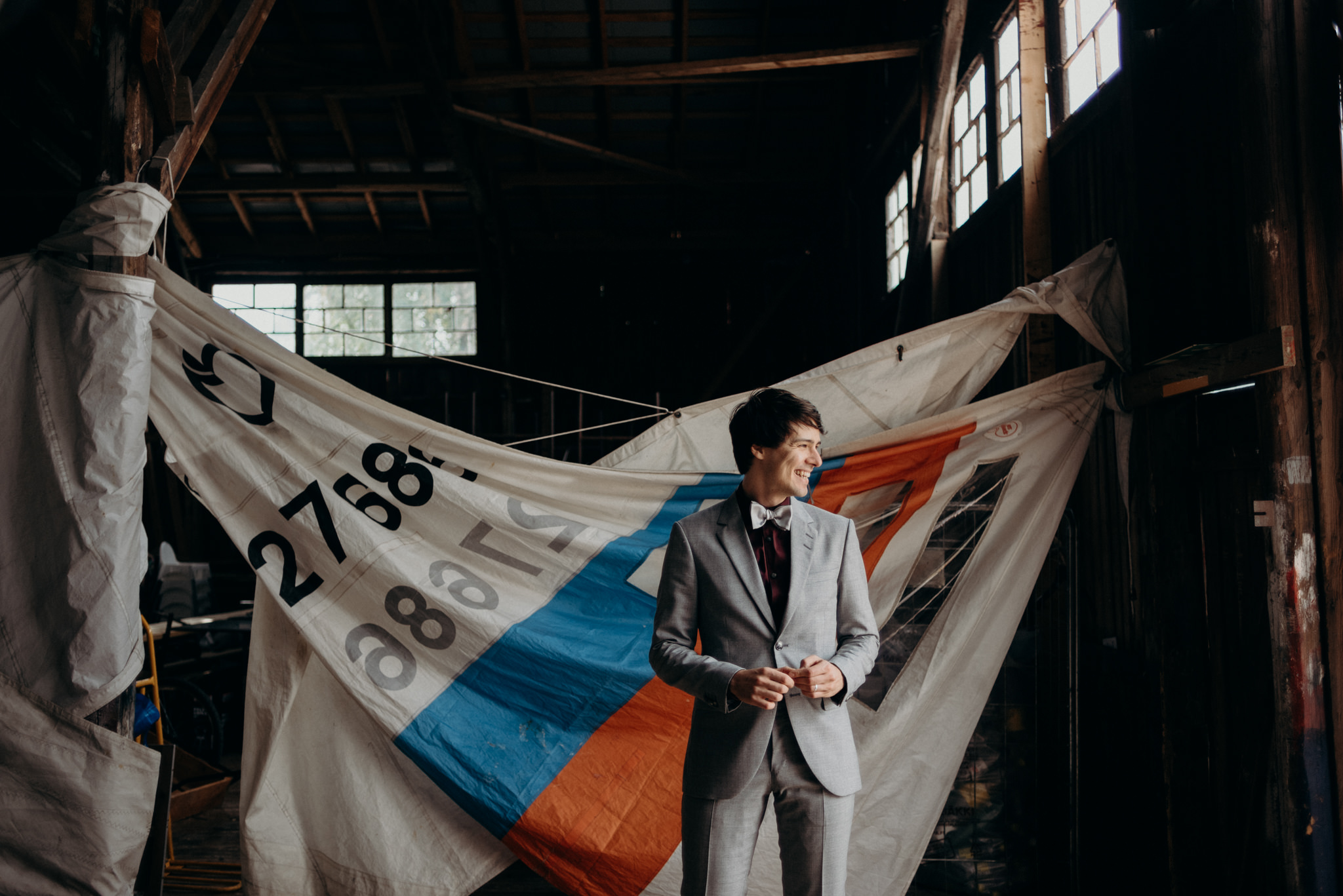 Groom standing in front of old sails in a boathouse Valkosaaren Telakka Helsinki