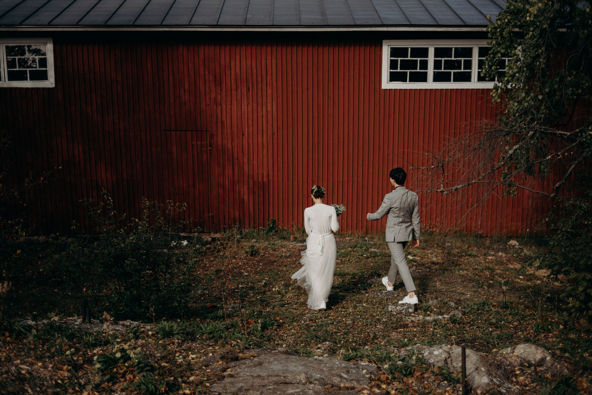 Bride and groom walking towards boathouse for portraits, Valkosaaren Telakka wedding