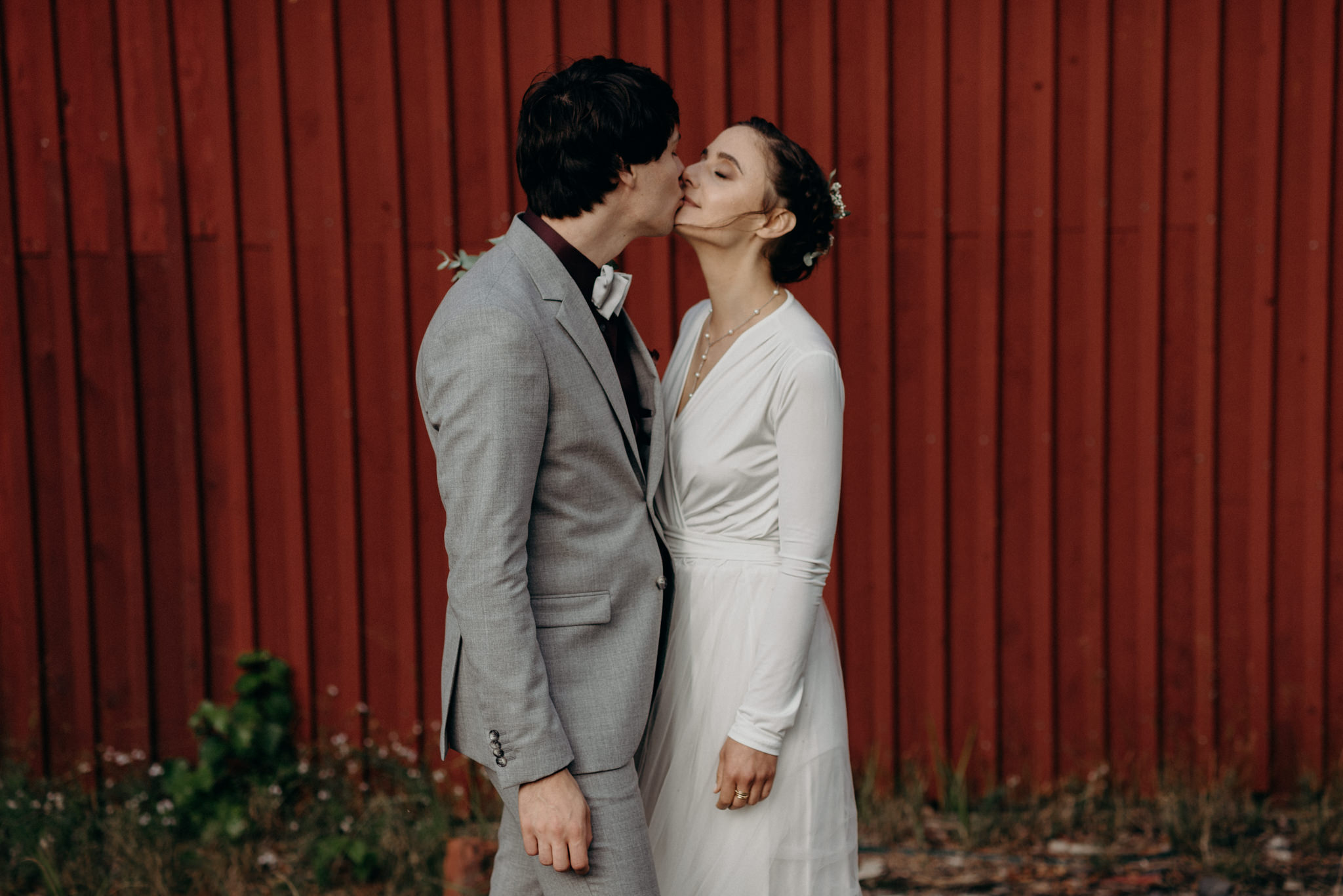 passionate kiss between bride and groom in front of red barn