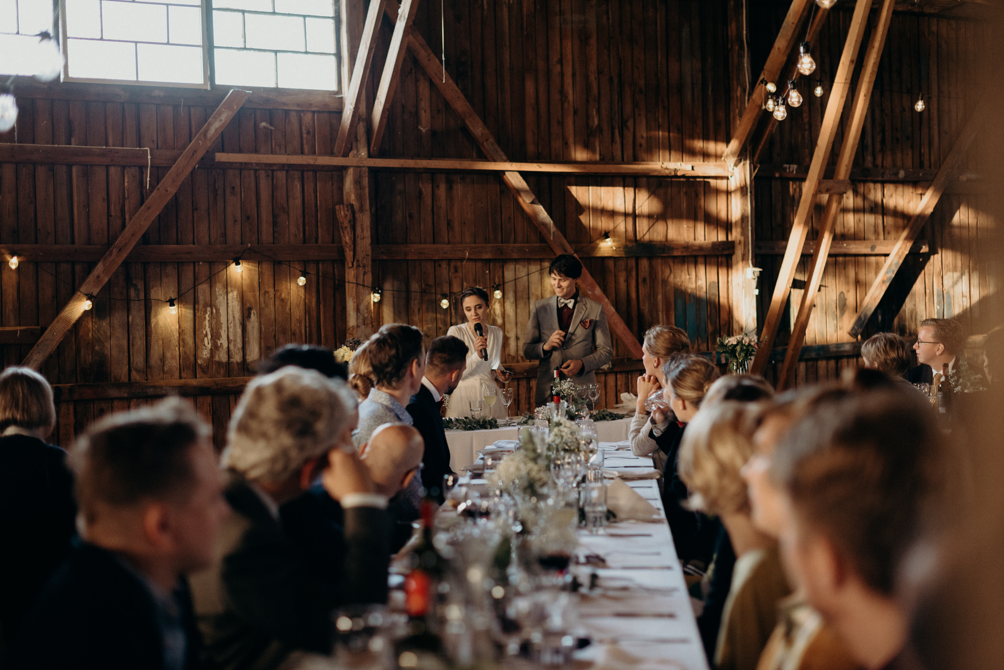 Guests listening and smiling during speeches at Valkosaaren Telakka wedding reception