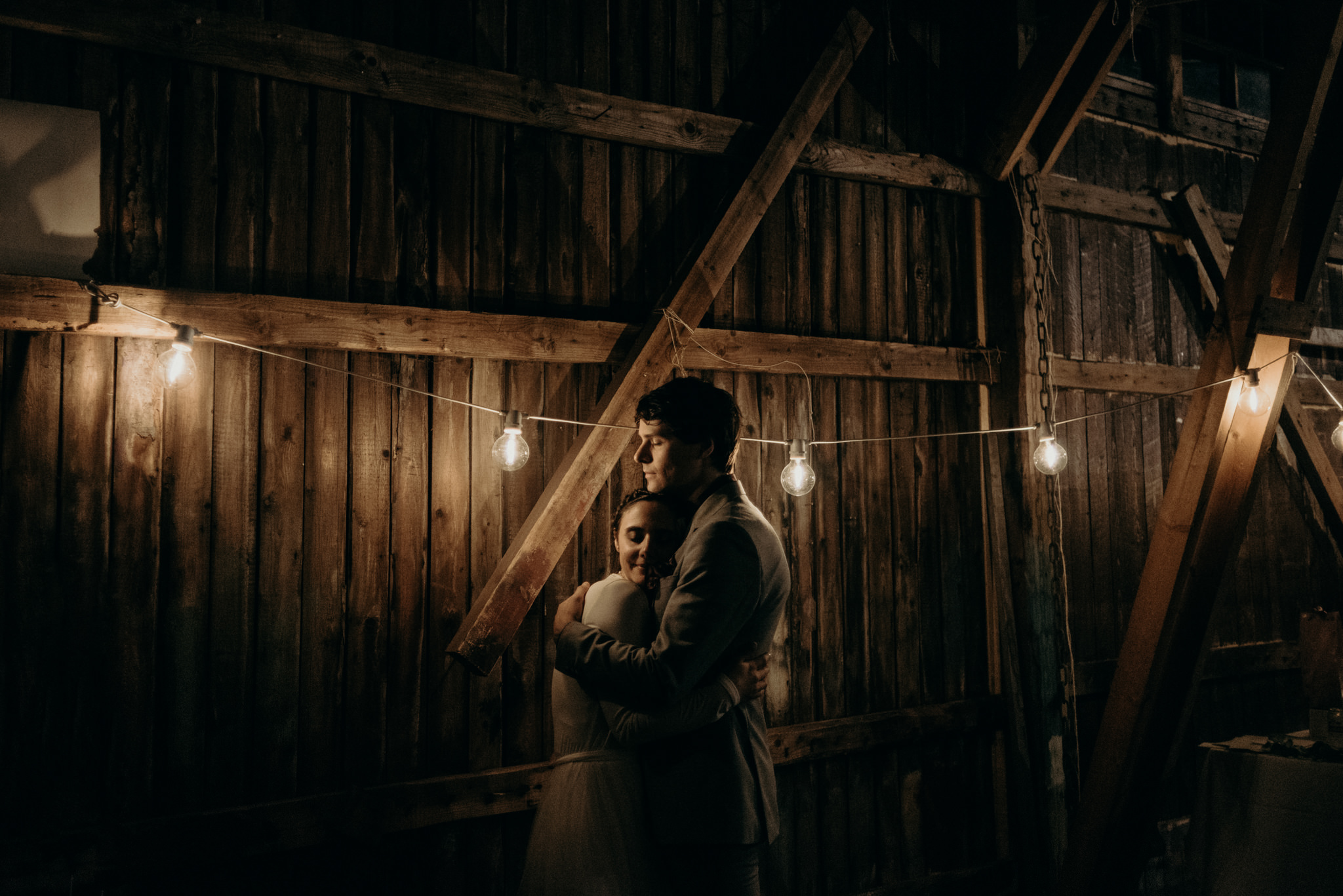 bride and groom kissing in old boathouse with stringlights at night