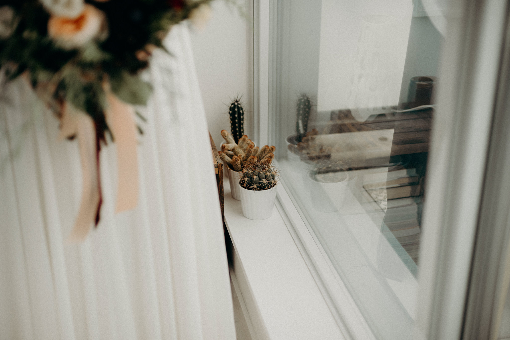 bride looking out window in bedroom holding bouquet and wearing floral crown