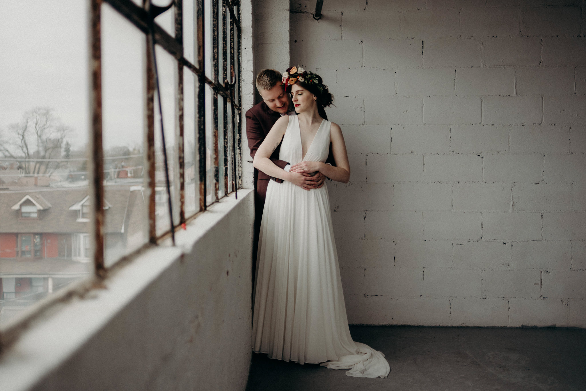 bride smiling and standing against white brick wall