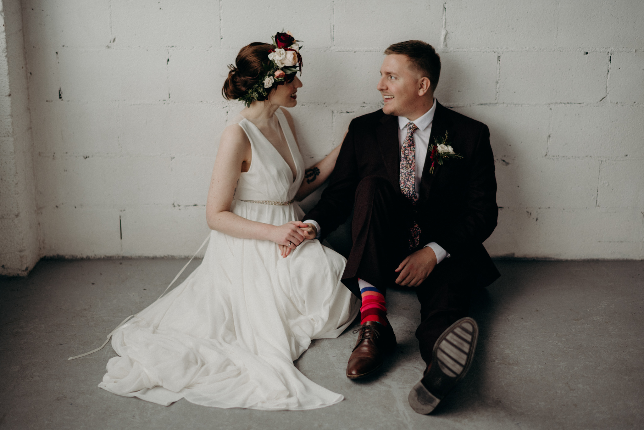 bride and groom hugging in front of large windows in old loft in Toronto