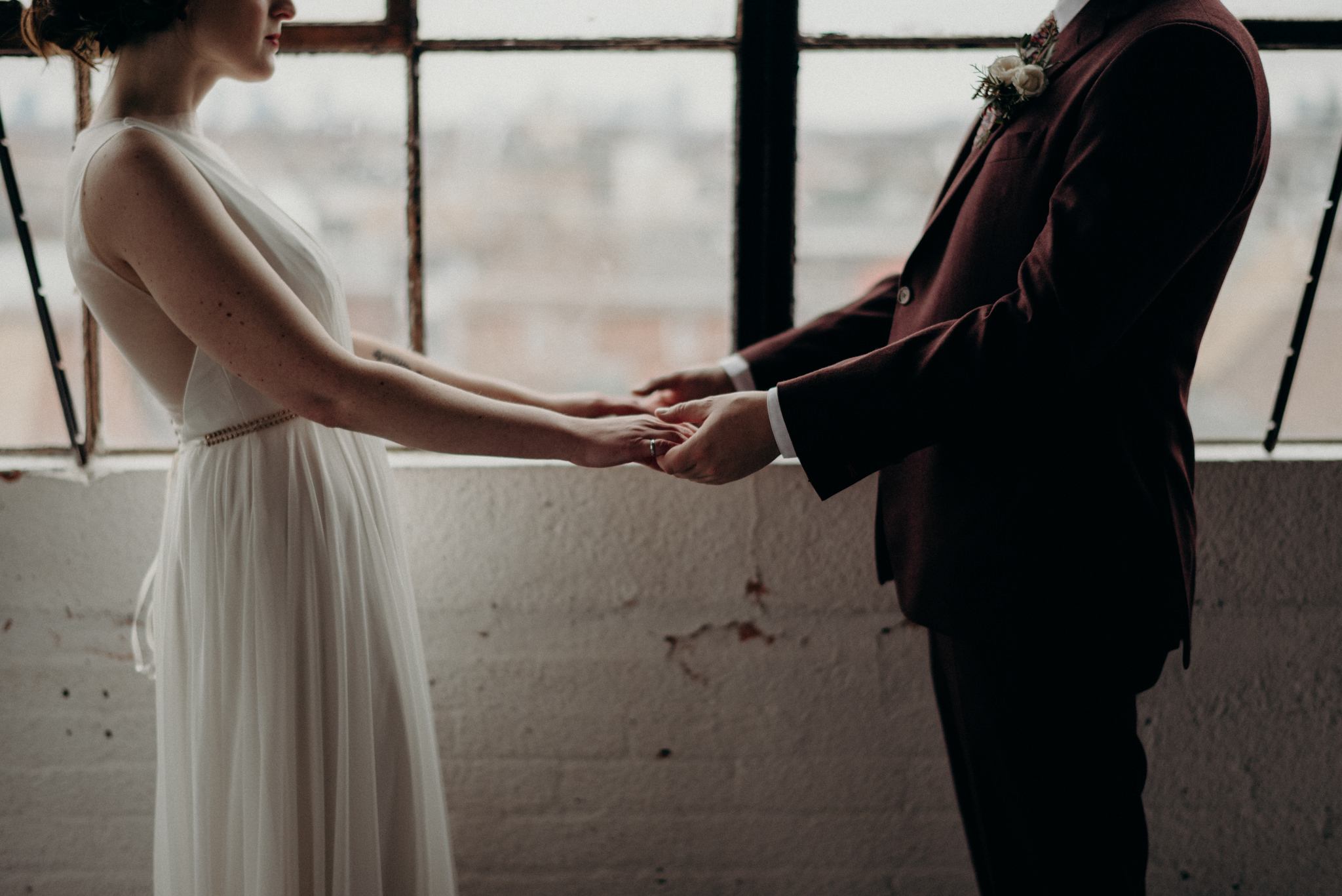 bride and groom sitting on concrete floor of old loft