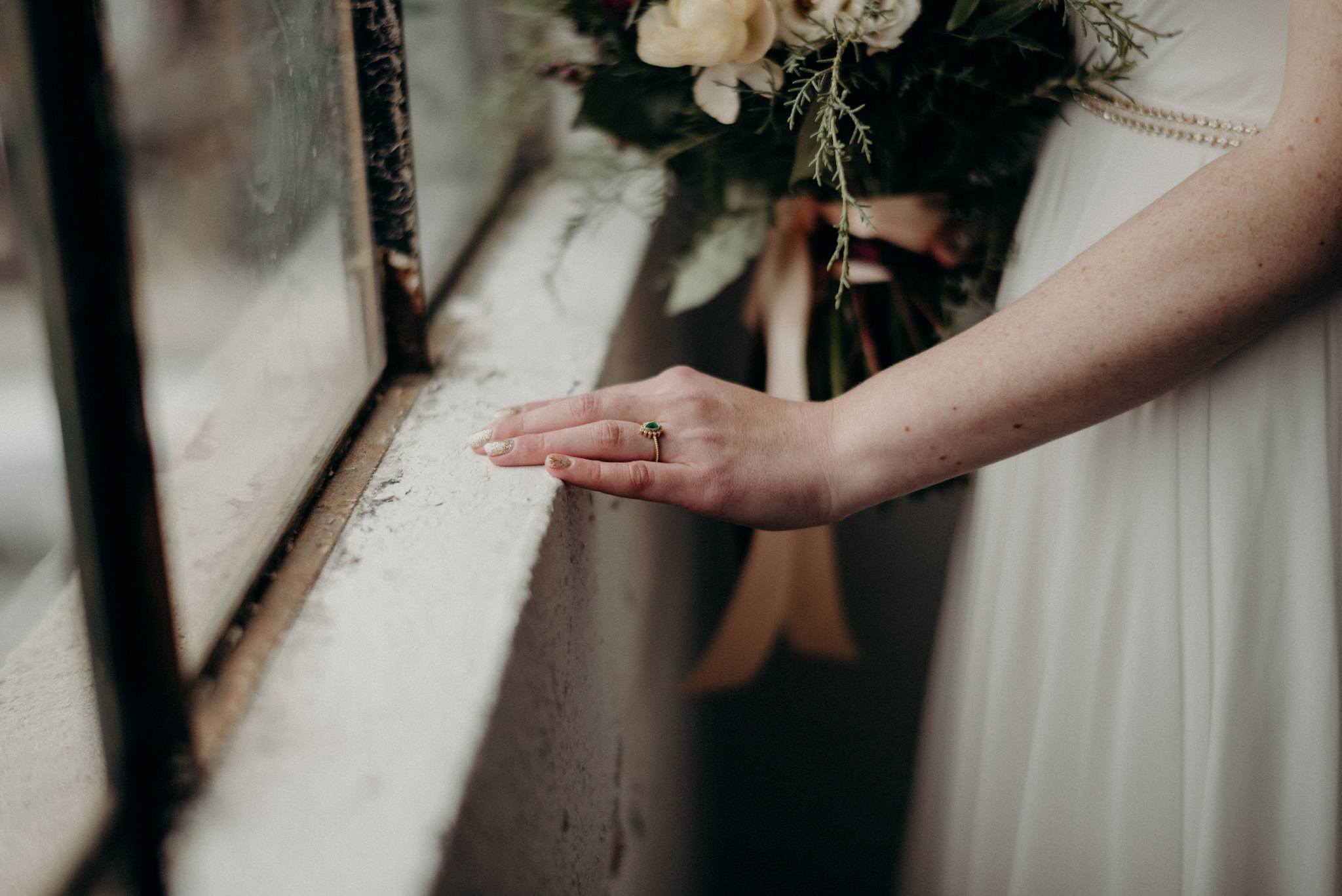 bride and groom holding hands in front of large windows of old loft in Toronto