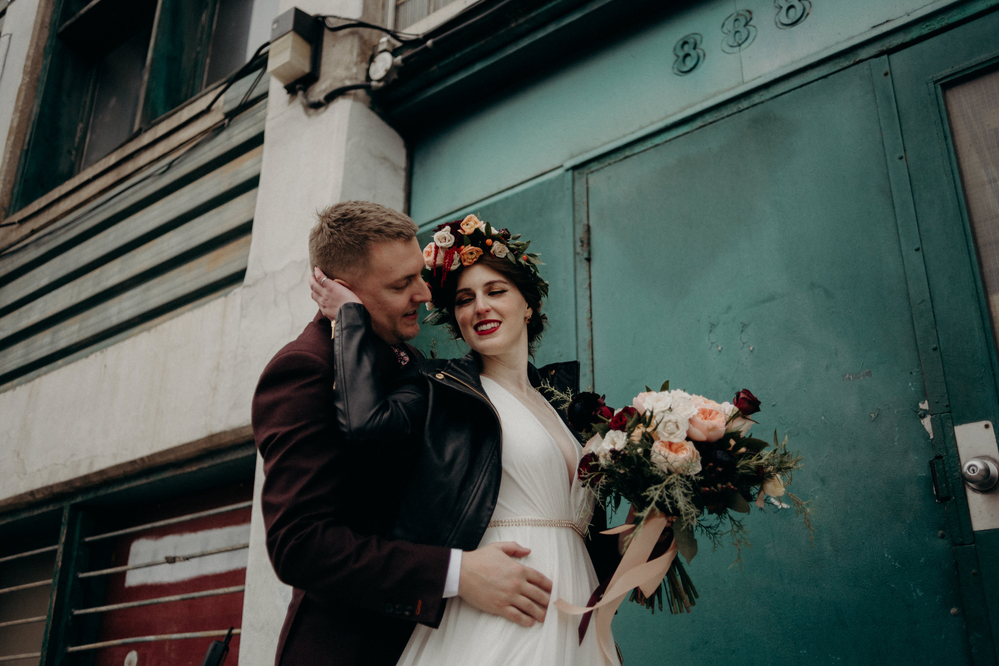 bride and groom leaning against white brick wall of old loft