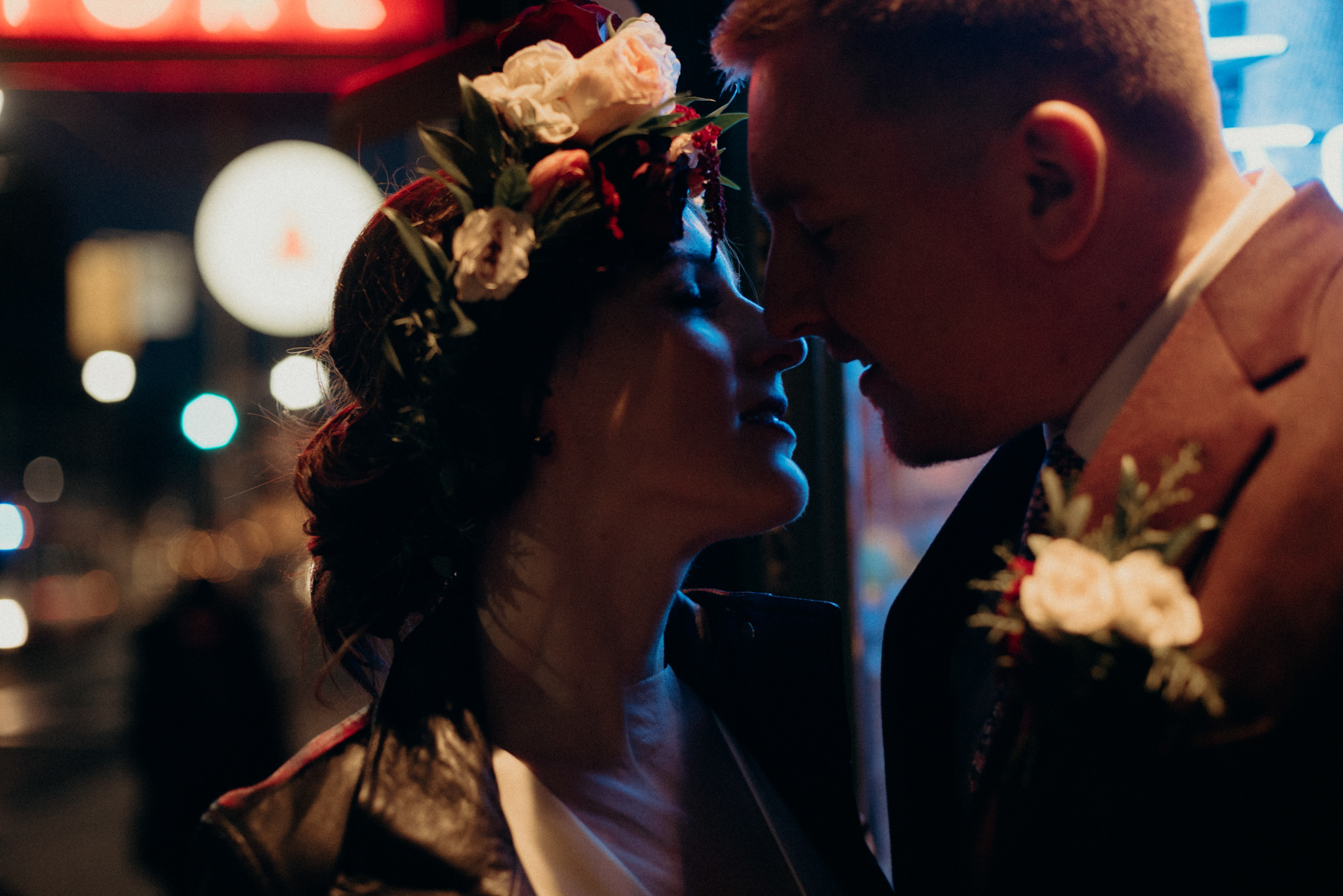 bride and groom sitting on front of neon signs of store