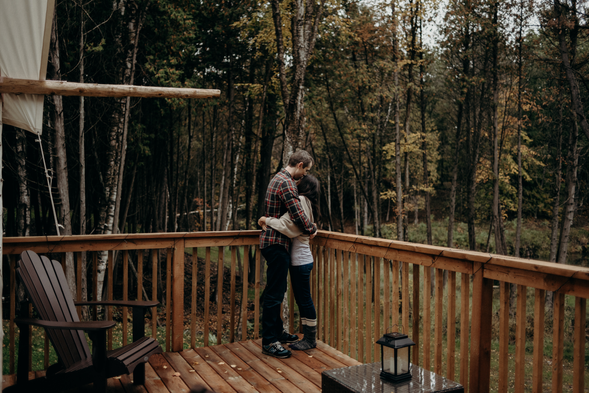 Couple hugging on deck surrounded by trees in the fall