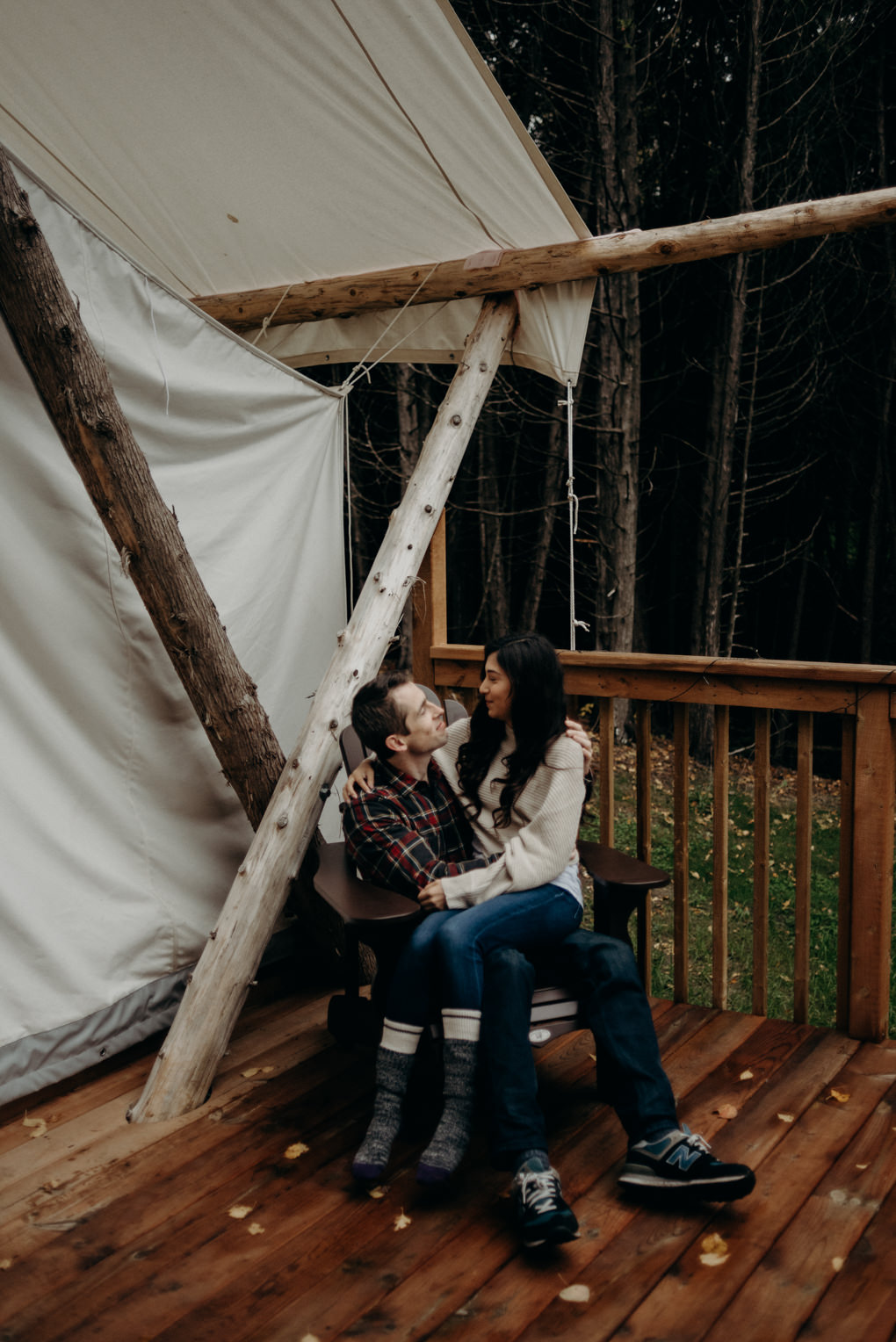 couple sitting in chair in front of glamping tent in the fall