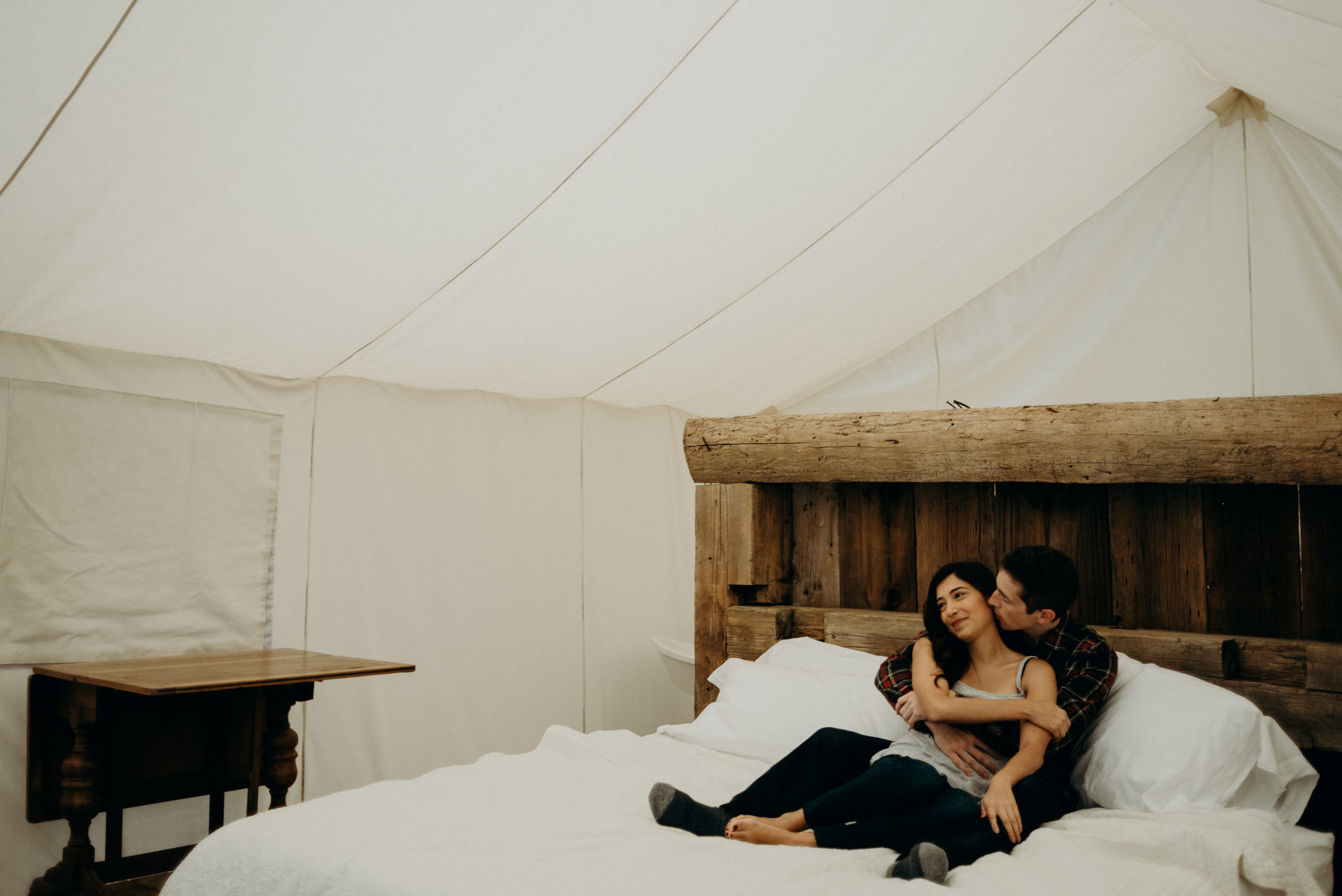 couple cuddling in bed in luxury glamping tent at Whispering Springs