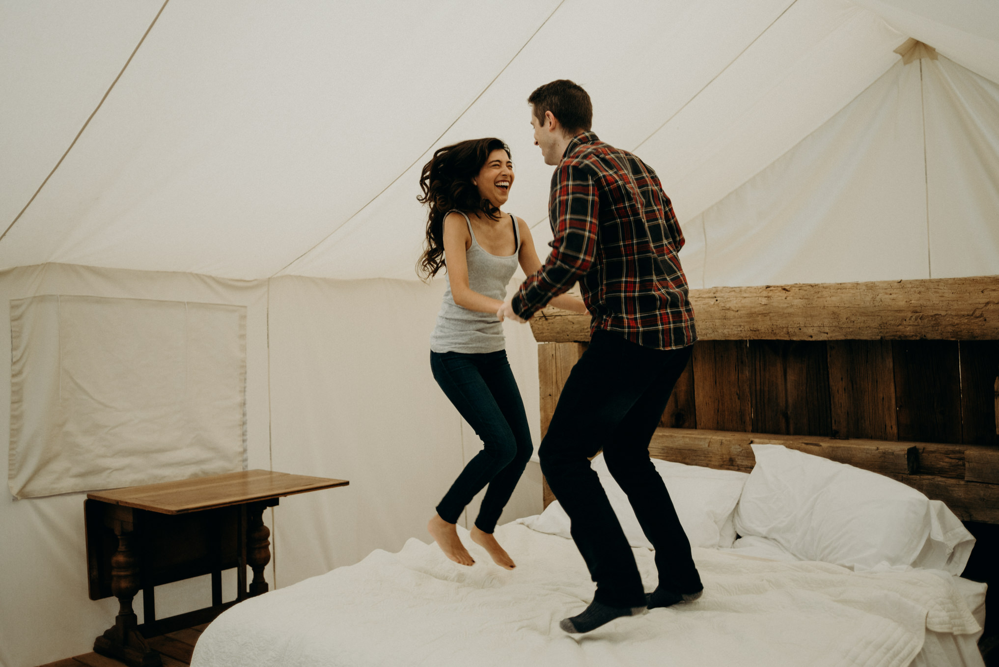 Couple jumping on bed in glamping tent at Whispering Springs