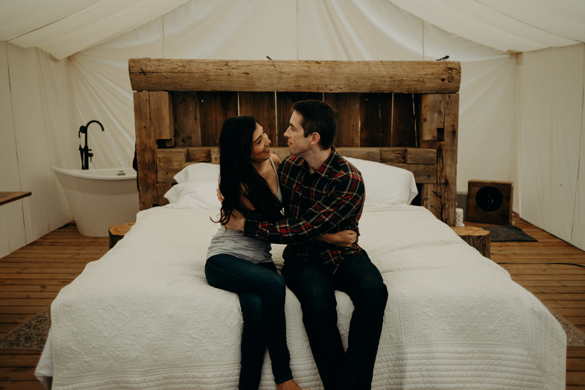 Couple sitting on bed in glamping tent at Whispering Springs