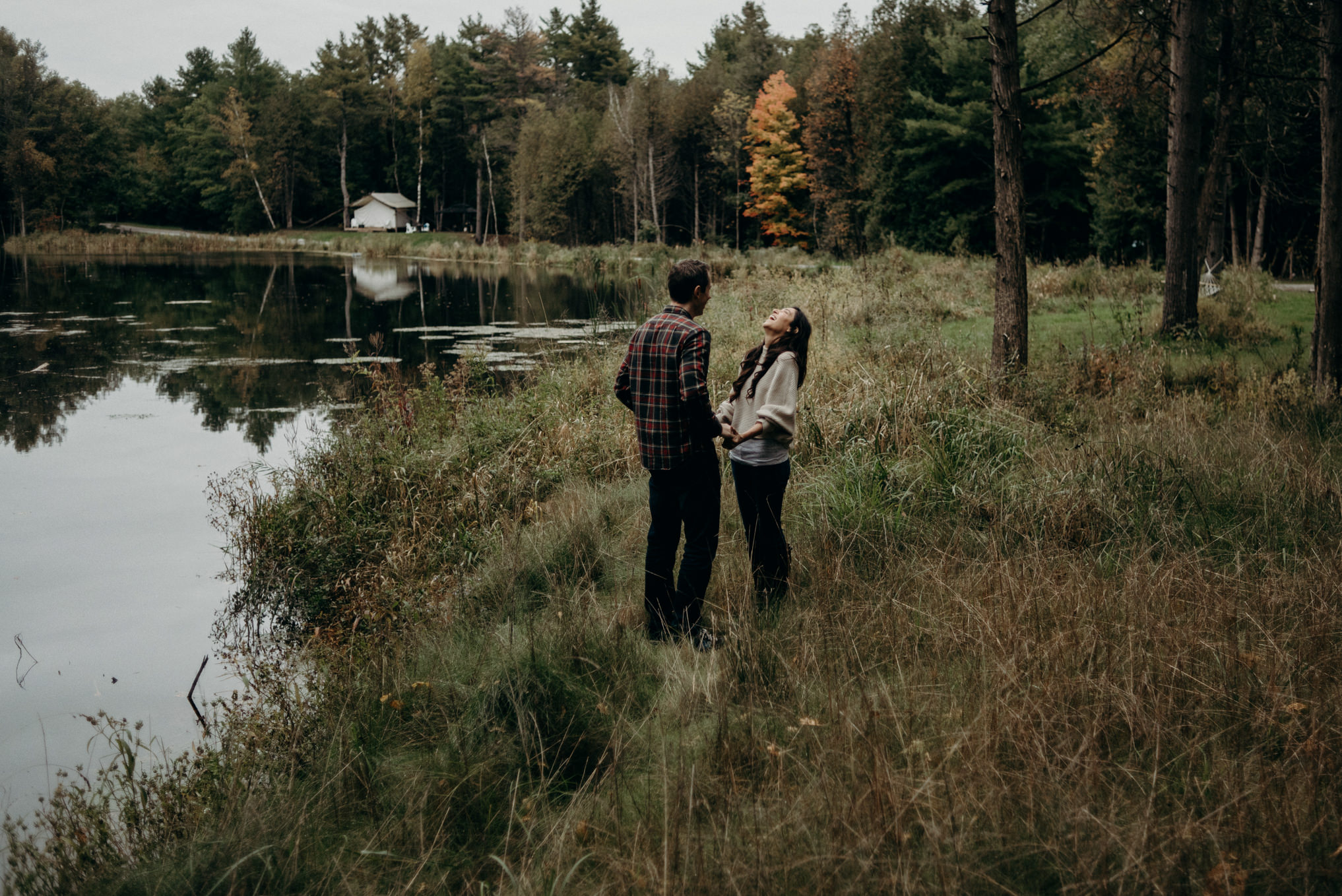 Couple laughing and hugging outside by water in the fall