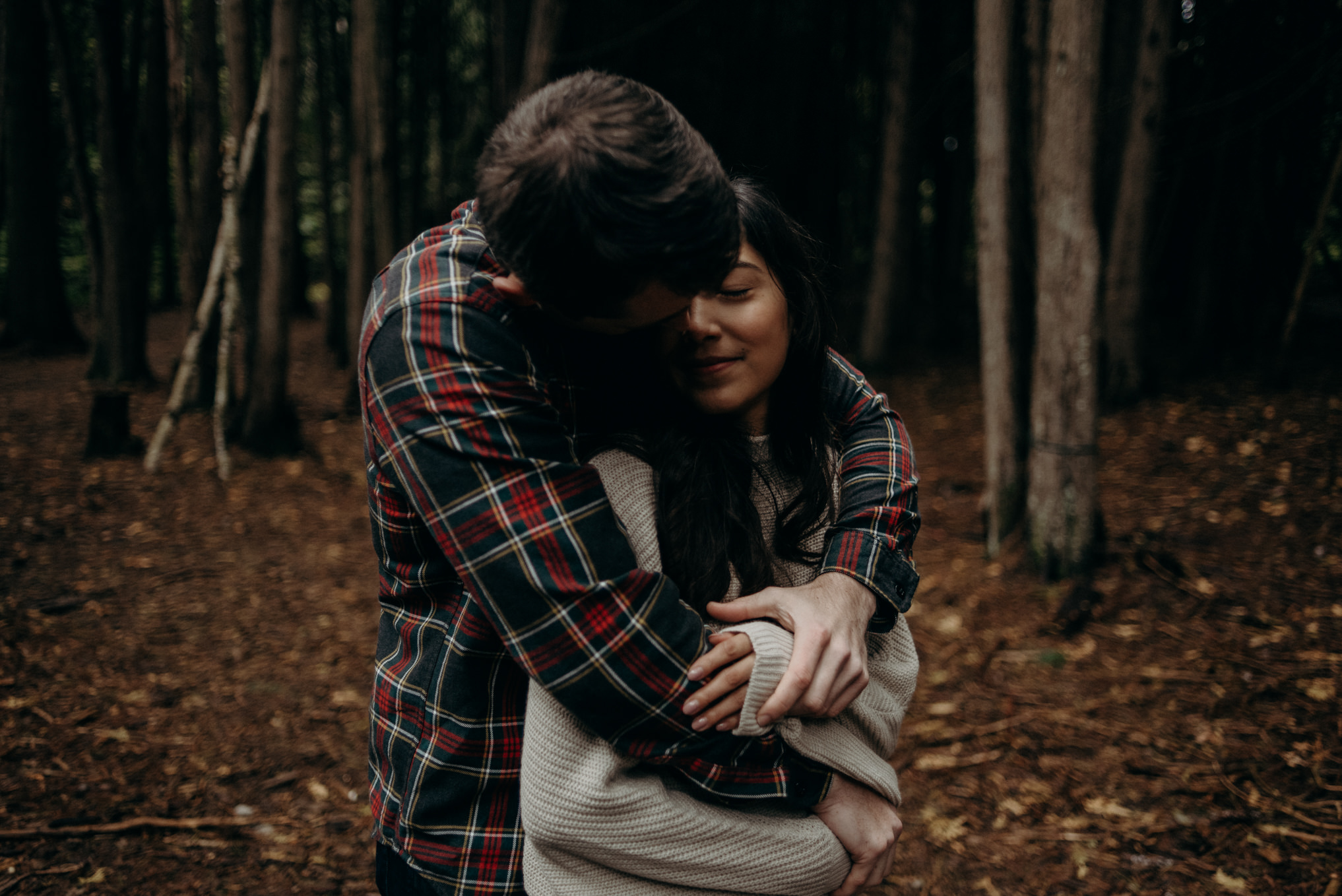 couple standing in a field beside trees