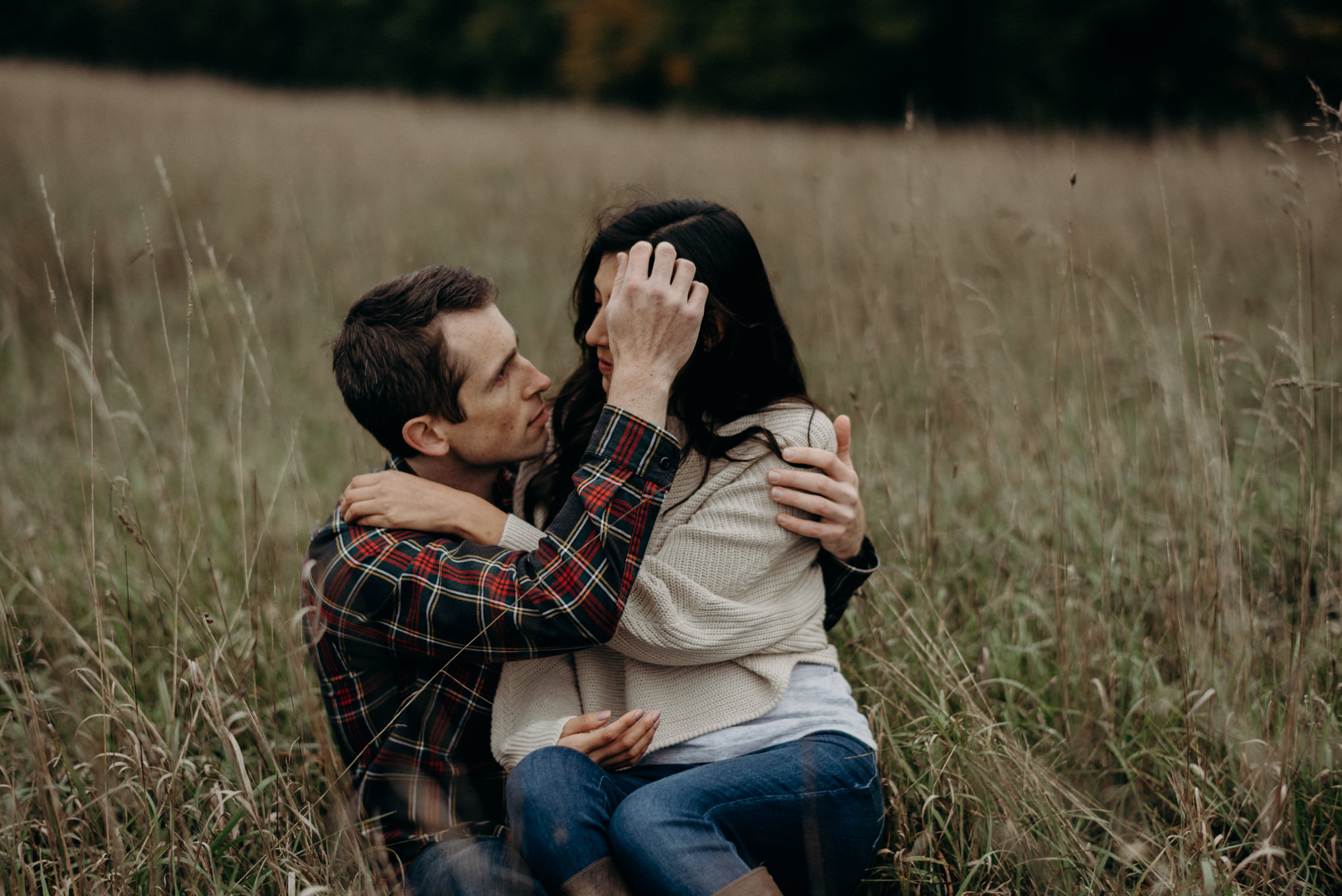 Couple cuddling in a field, fall engagement shoot