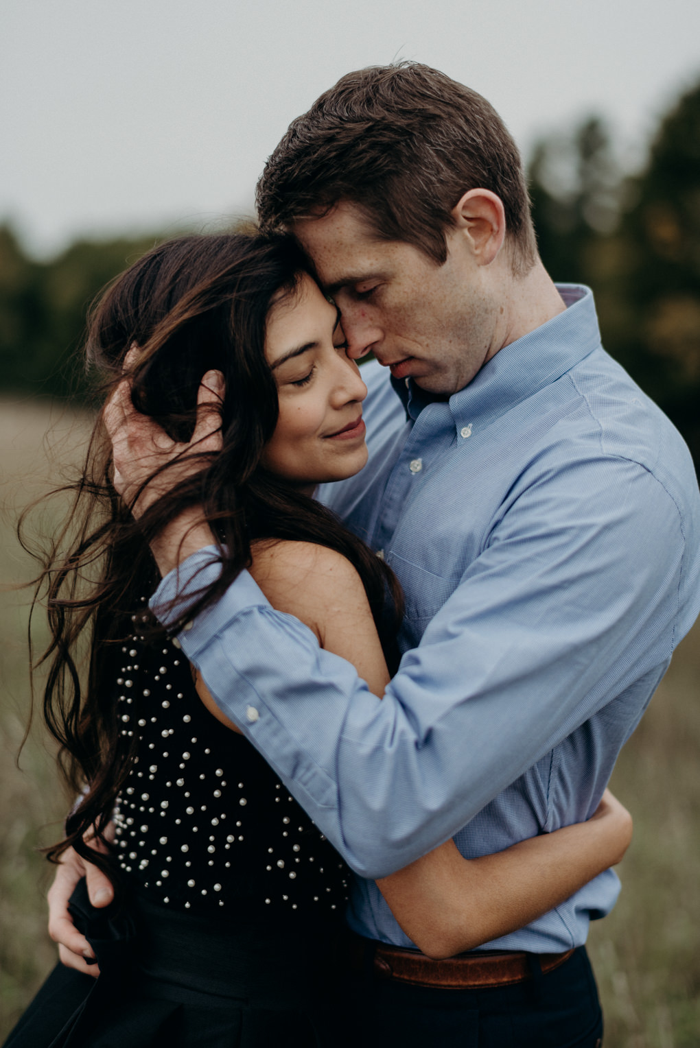 couple holding hands and walking through field