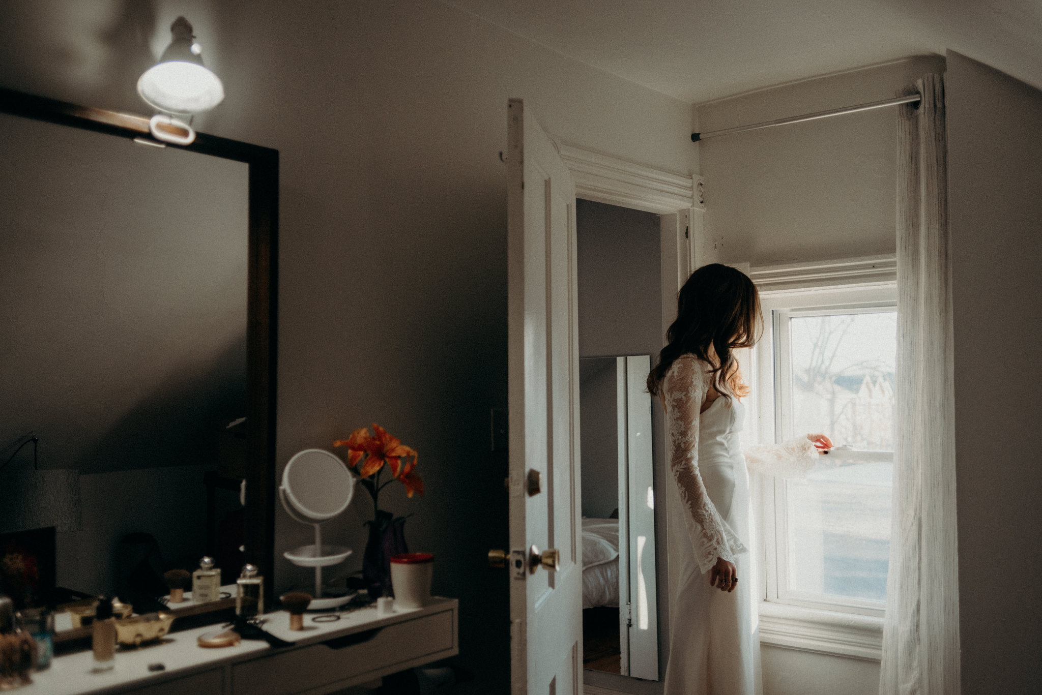 bride in wedding dress standing by window