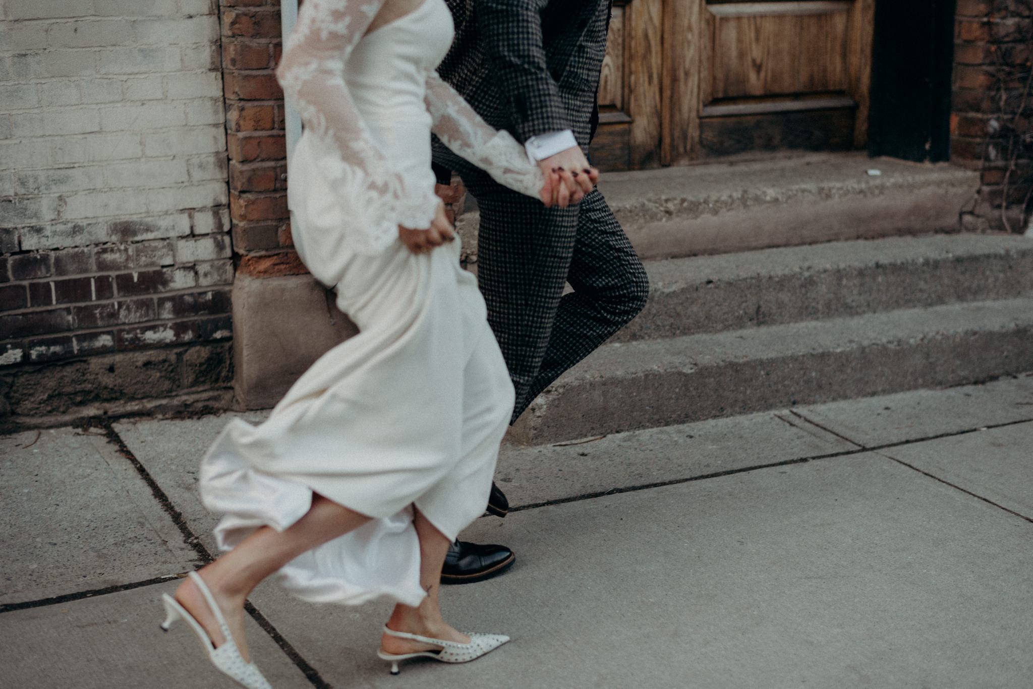 bride and groom running on sidewalk holding hands