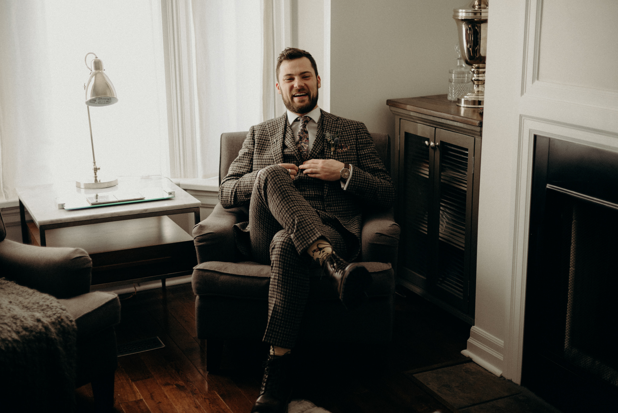 groom in wool suit sitting in chair in living room