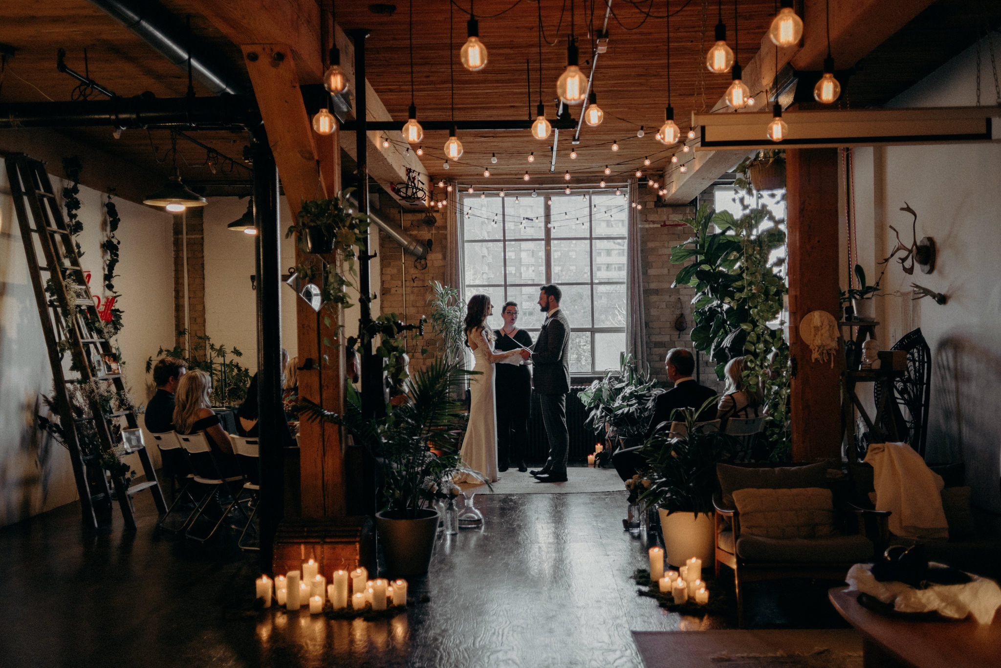 Bride and officiant wiping tears during wedding ceremony as groom reads vows