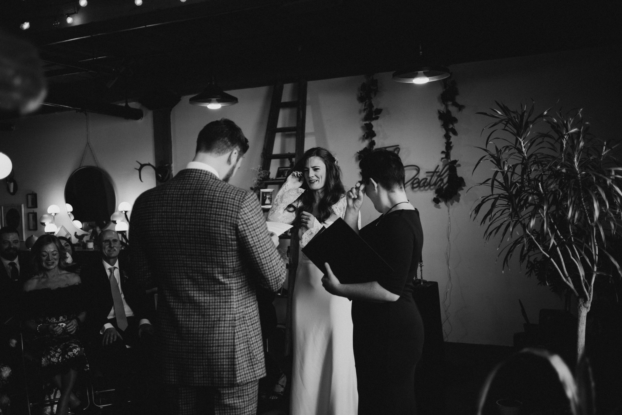 black and white image of bride and groom kissing during wedding ceremony in loft in Toronto