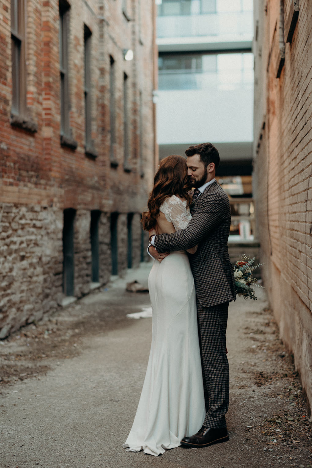 groom hugging bride in alleyway