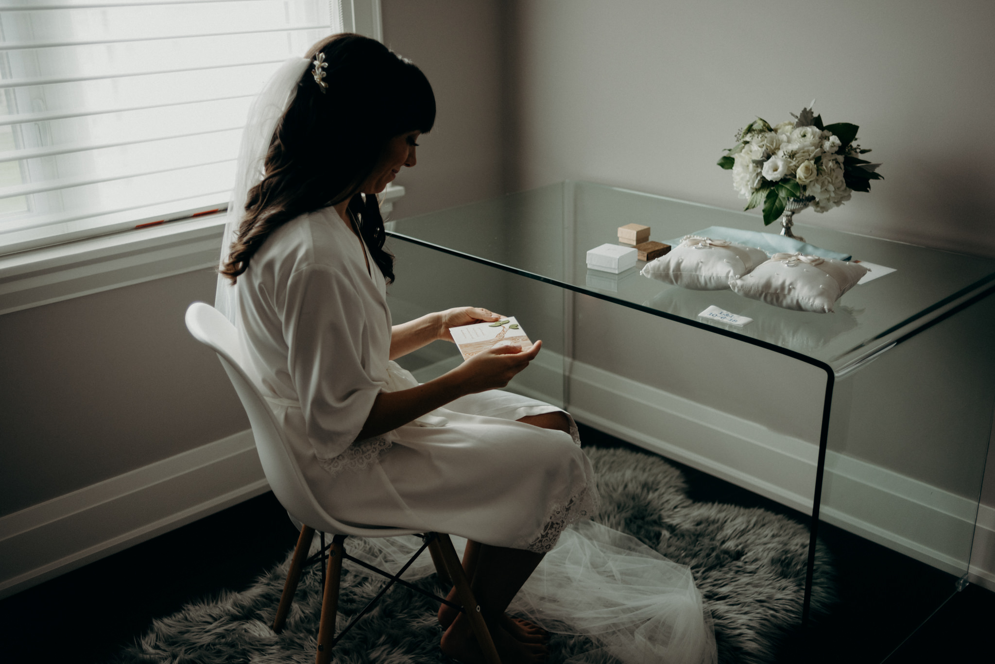 bride sitting in chair reading card while getting ready