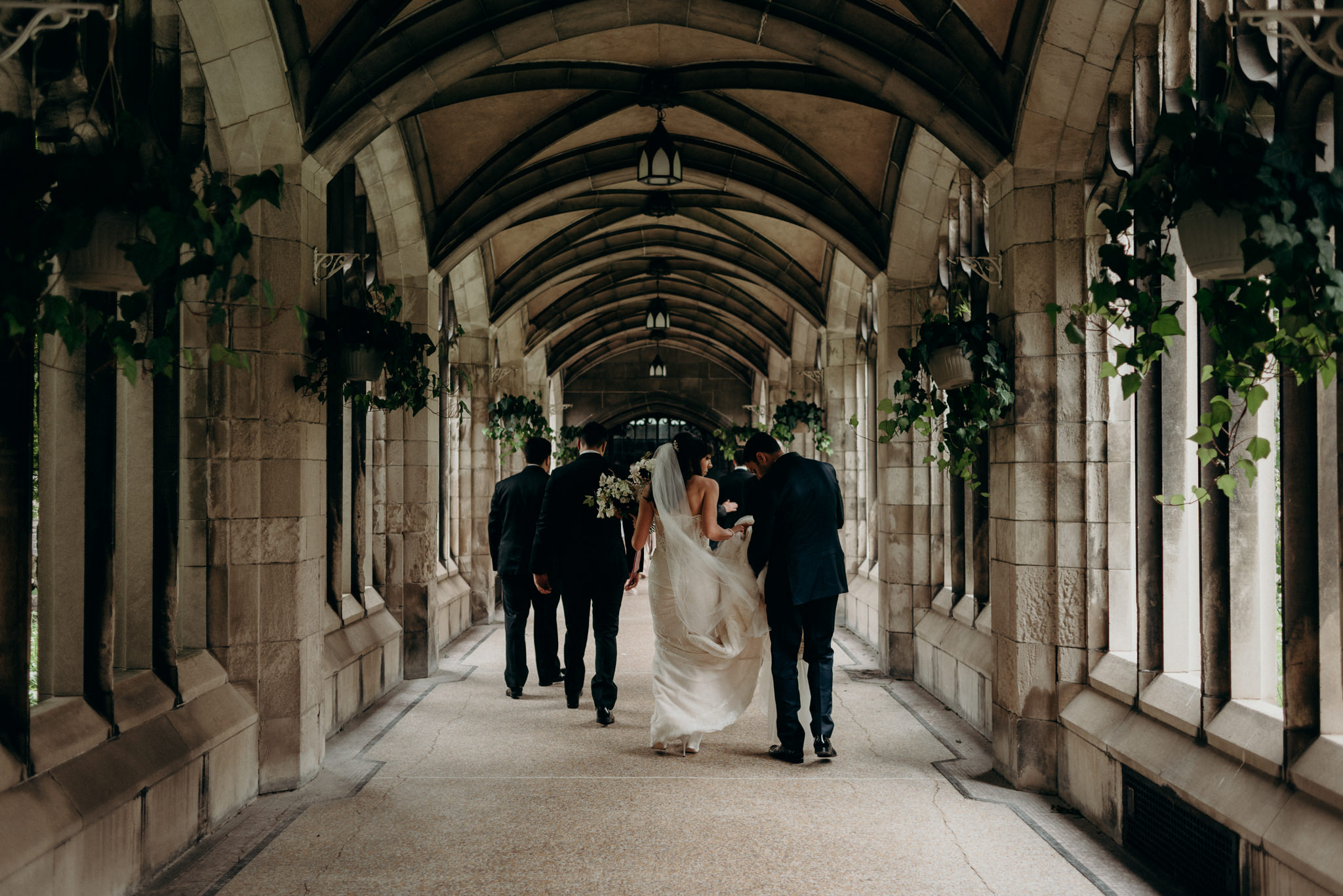 Wedding party walking in archway at Knox College University of Toronto