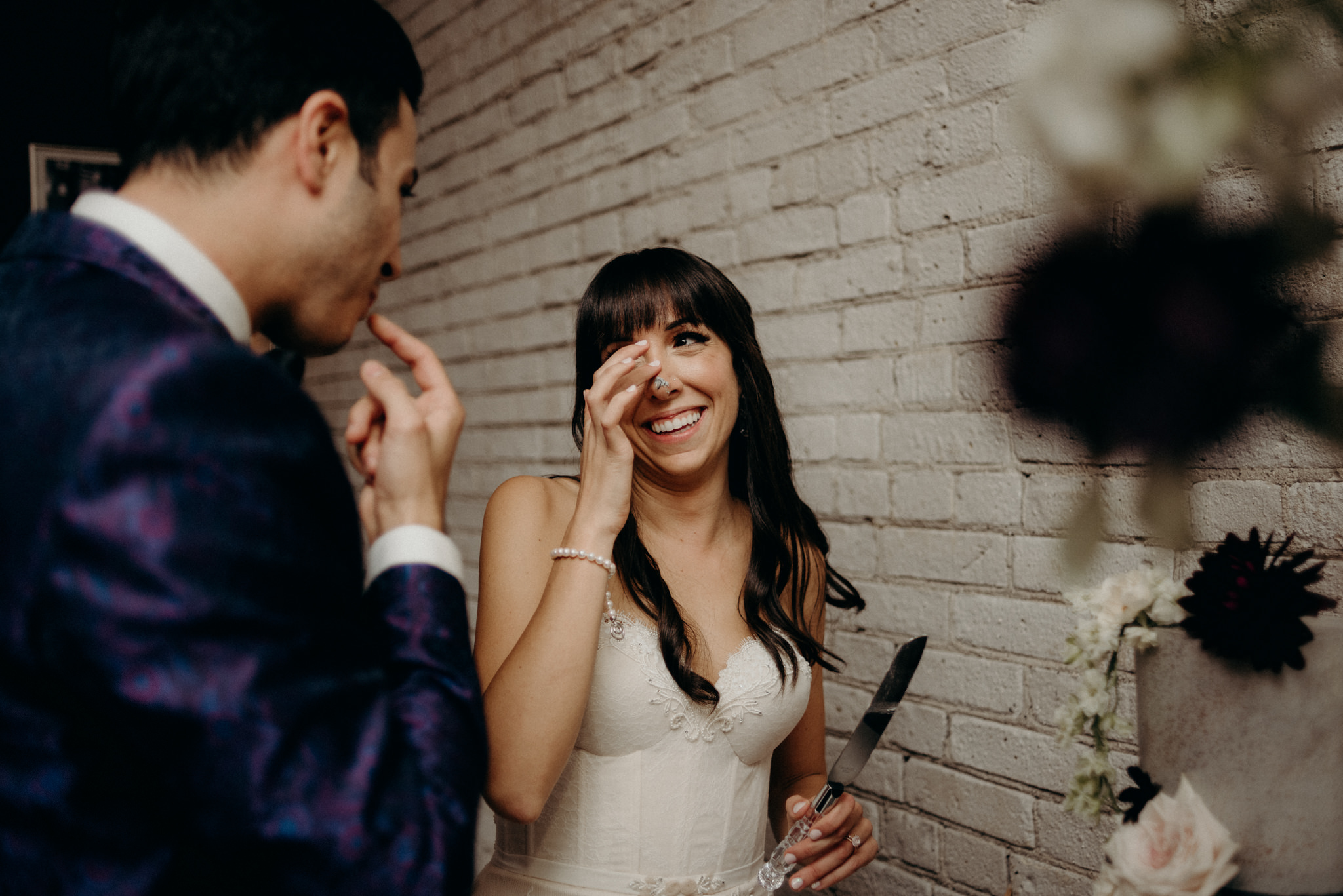 Bride wiping icing off nose during cake cutting