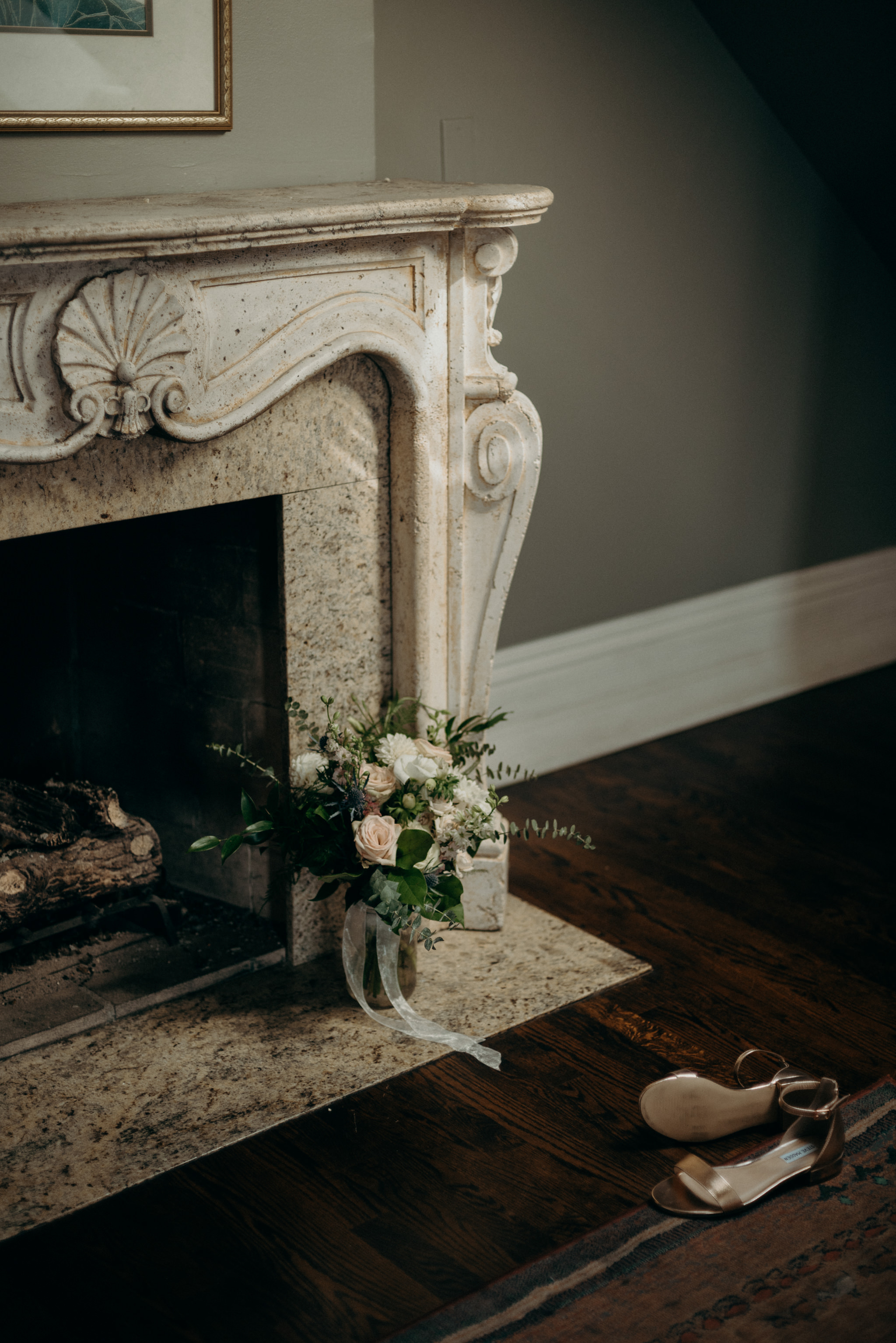 wedding bouquet and shoes on ground in front of elegant vintage fireplace