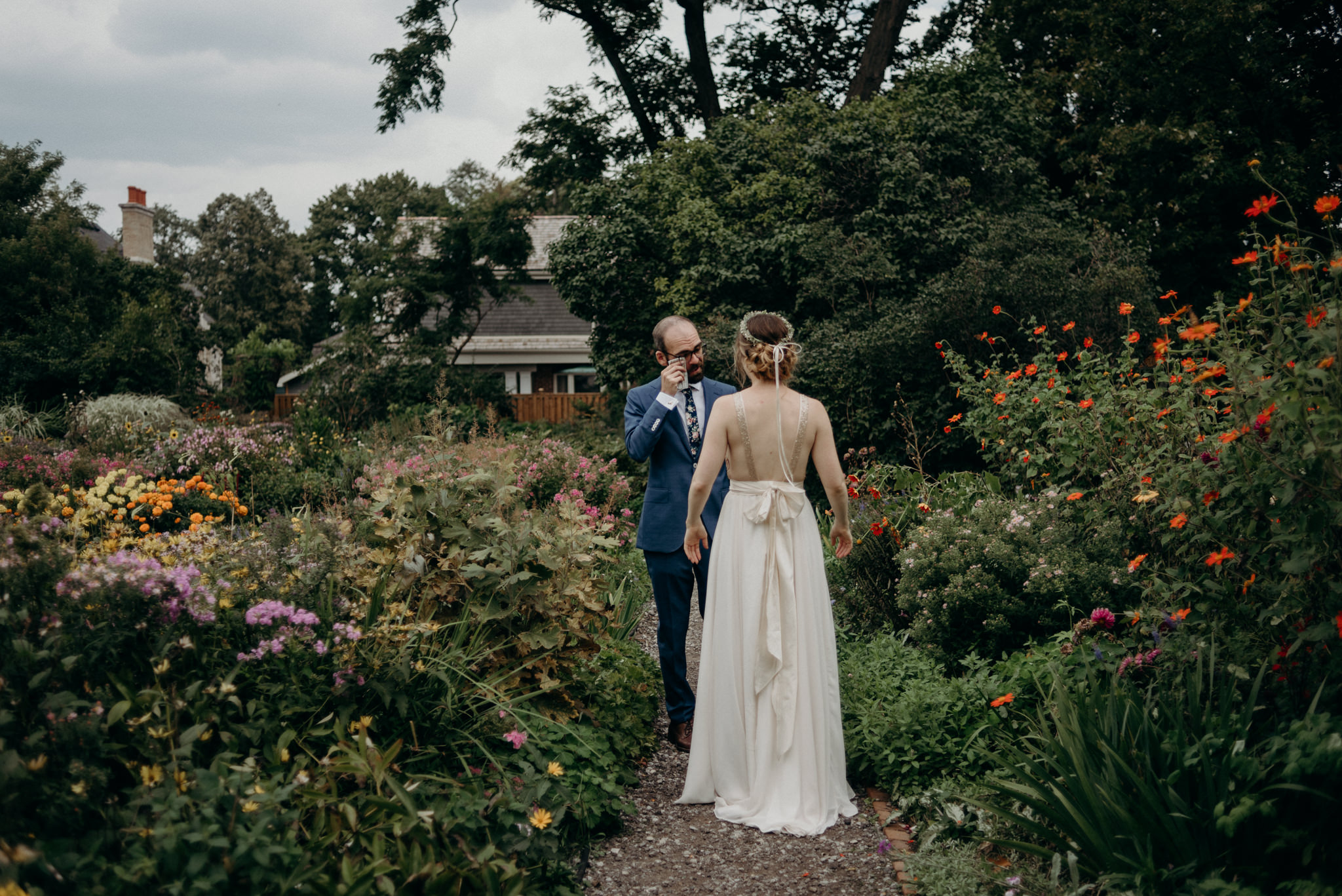 groom wiping tears from eyes after first look in gardens at Spadina Museum